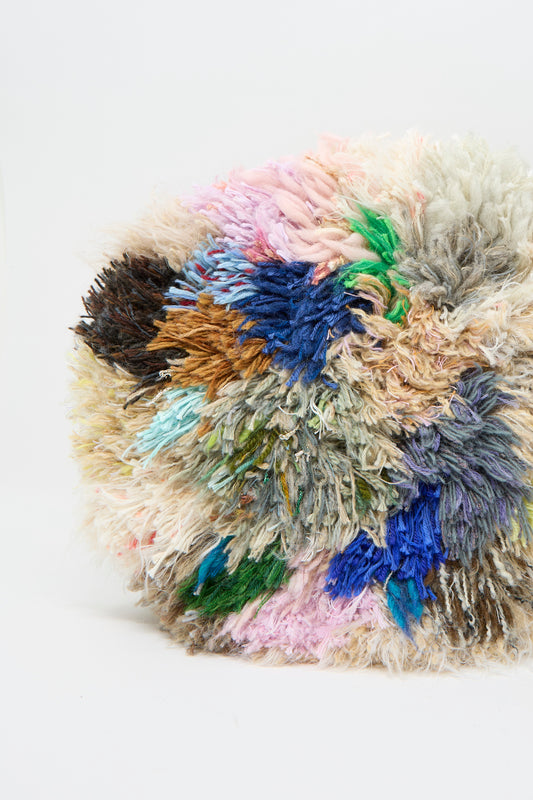 The Handmade Cushion in Multi X by Renilde De Peuter features a fluffy, multicolored design with vibrant threads and recycled yarns on a white background. 