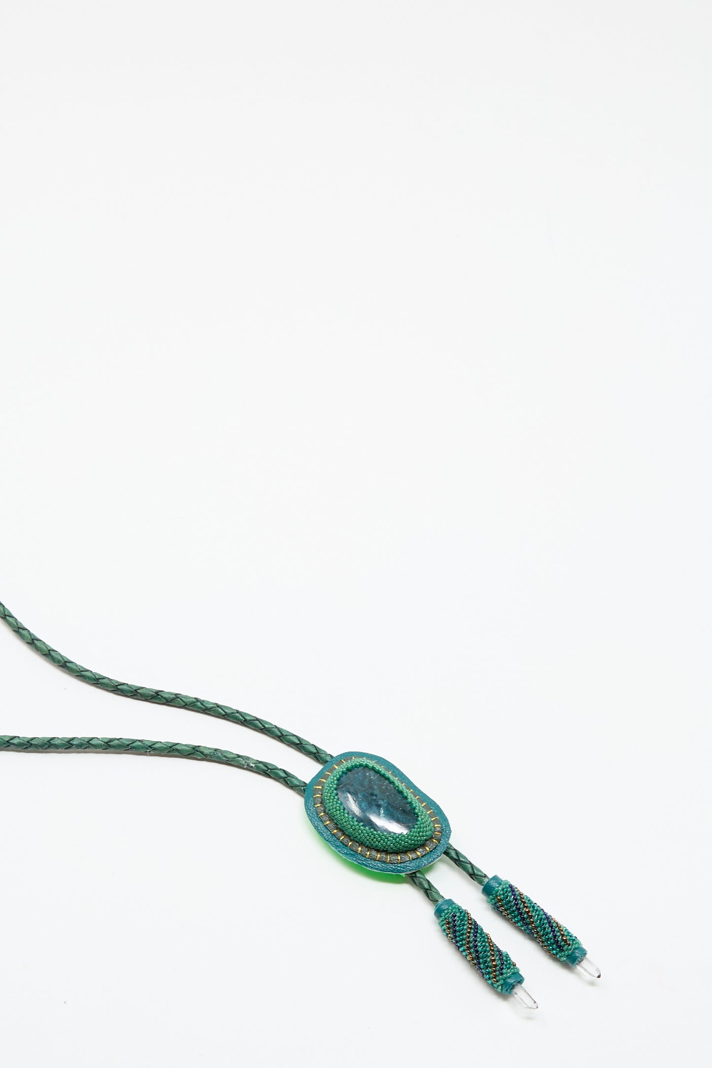 The Robin Mollicone Bolo Necklace in Apatite and Quartz features a green braided cord, a large oval Apatite gemstone pendant, and two decorative ends, shown on a white background.
