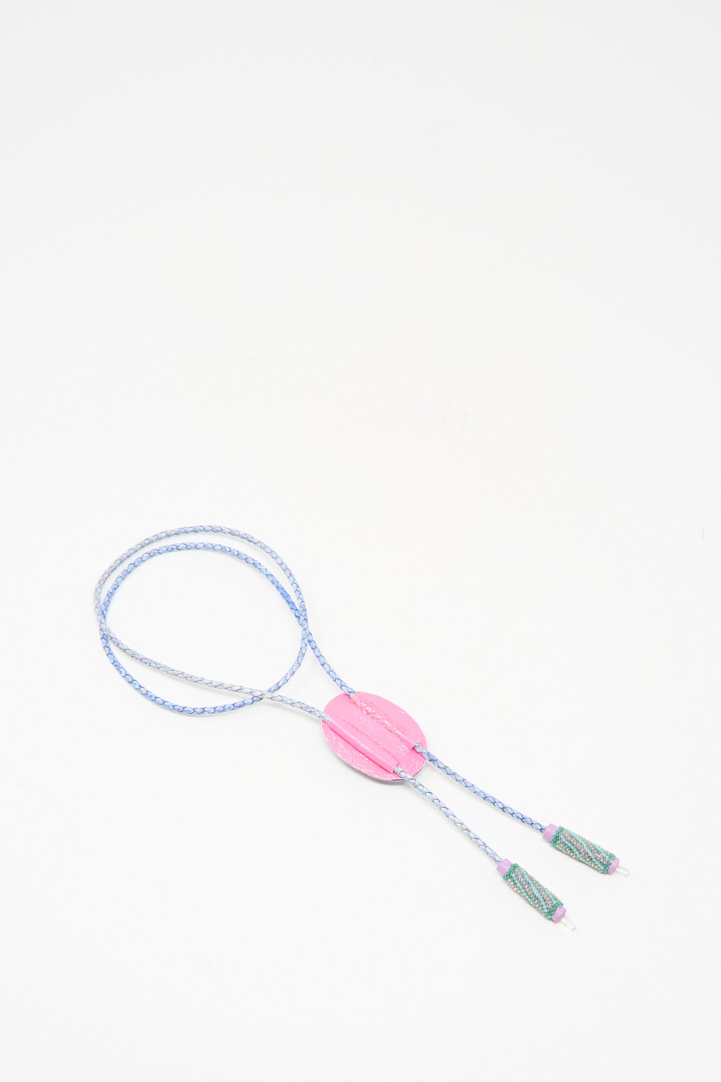 The Robin Mollicone Bolo Necklace in Kunzite and Quartz is a handmade blue and white braided cord necklace with a large pink oval bead center and two green tassels, shown on a white background.