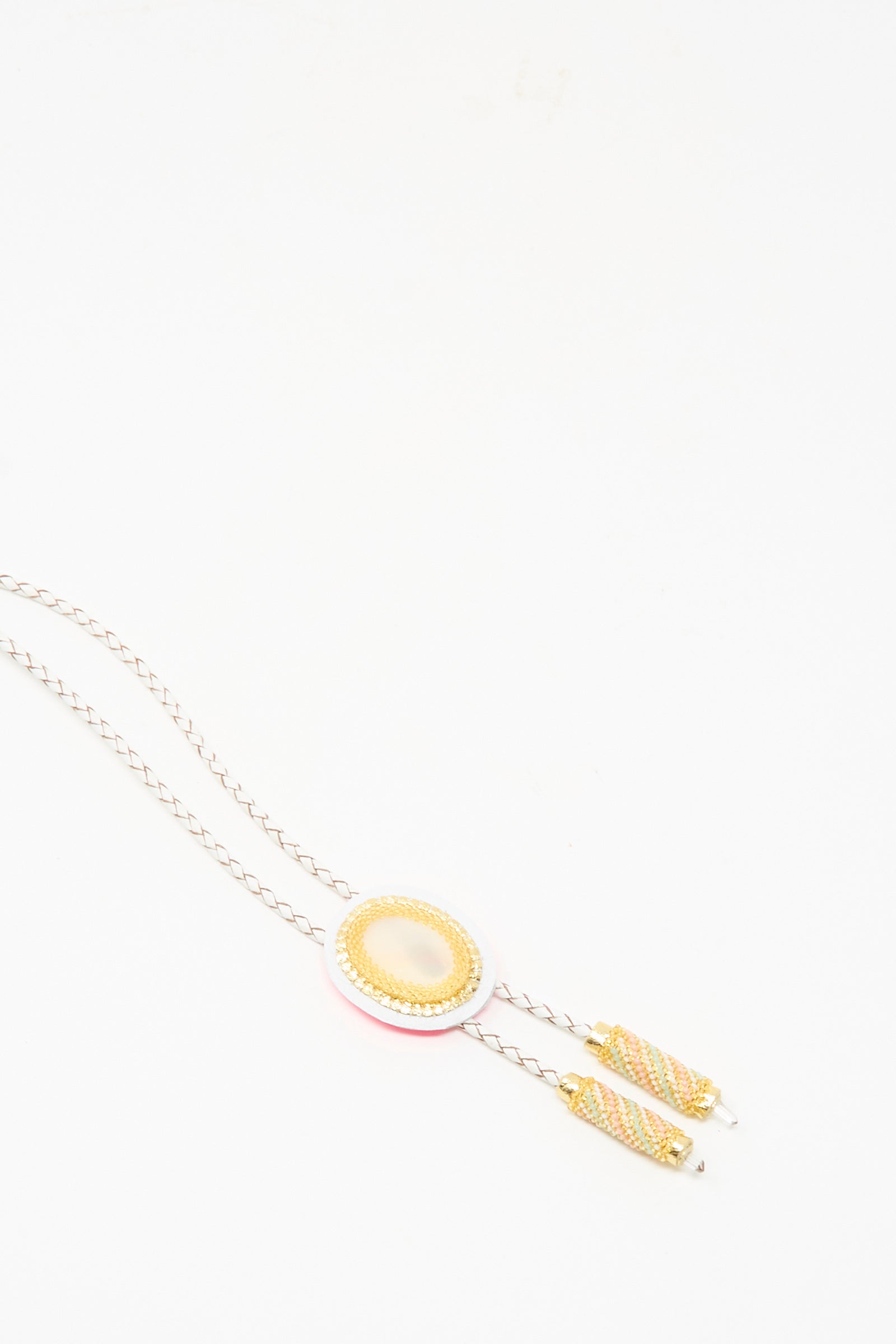 The Robin Mollicone Bolo Necklace features an oval Mother of Pearl and Quartz pendant on a slim, twisted chain with gold-capped ends, inspired by a modern bolo tie and displayed against a white background.