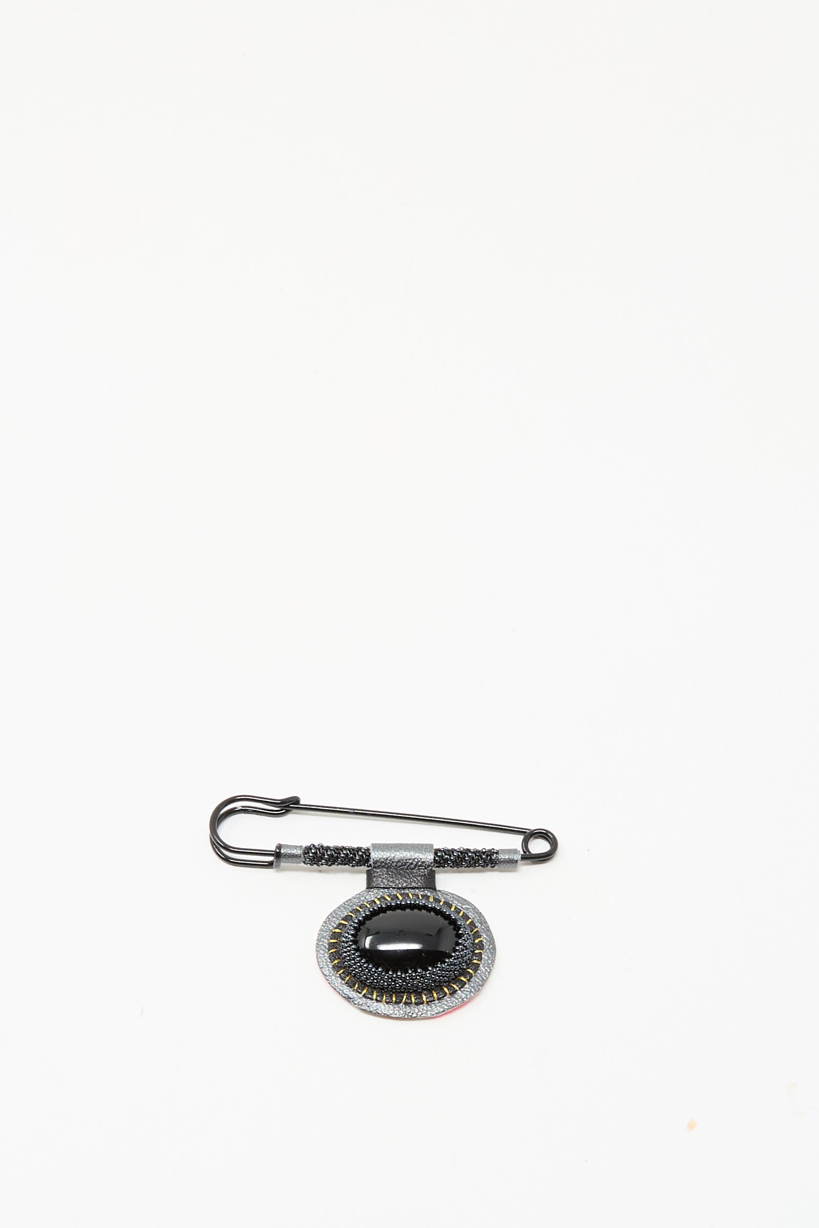 The Robin Mollicone Brooch in Onyx features a black safety pin and an oval pendant with black and silver accents, creating a striking statement against a plain white background.