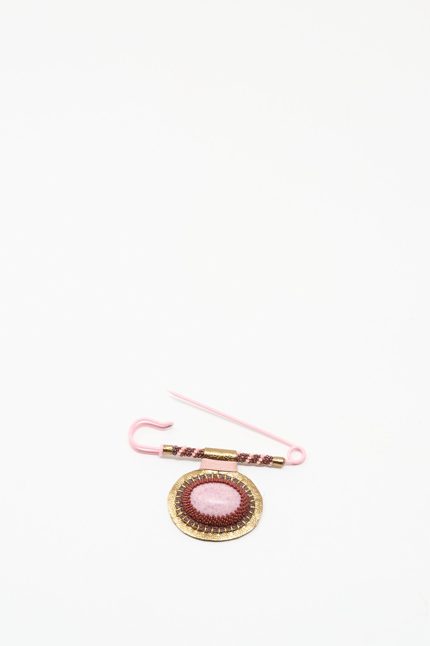 The Brooch in Rhodonite by Robin Mollicone is a handmade pink and gold pin from NYC, showcasing a round embroidered embellishment on a plain white background.