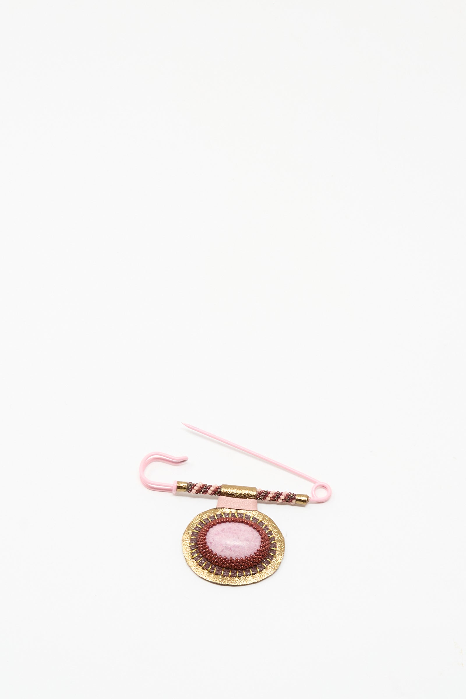 The Brooch in Rhodonite by Robin Mollicone is a handmade pink and gold pin from NYC, showcasing a round embroidered embellishment on a plain white background.