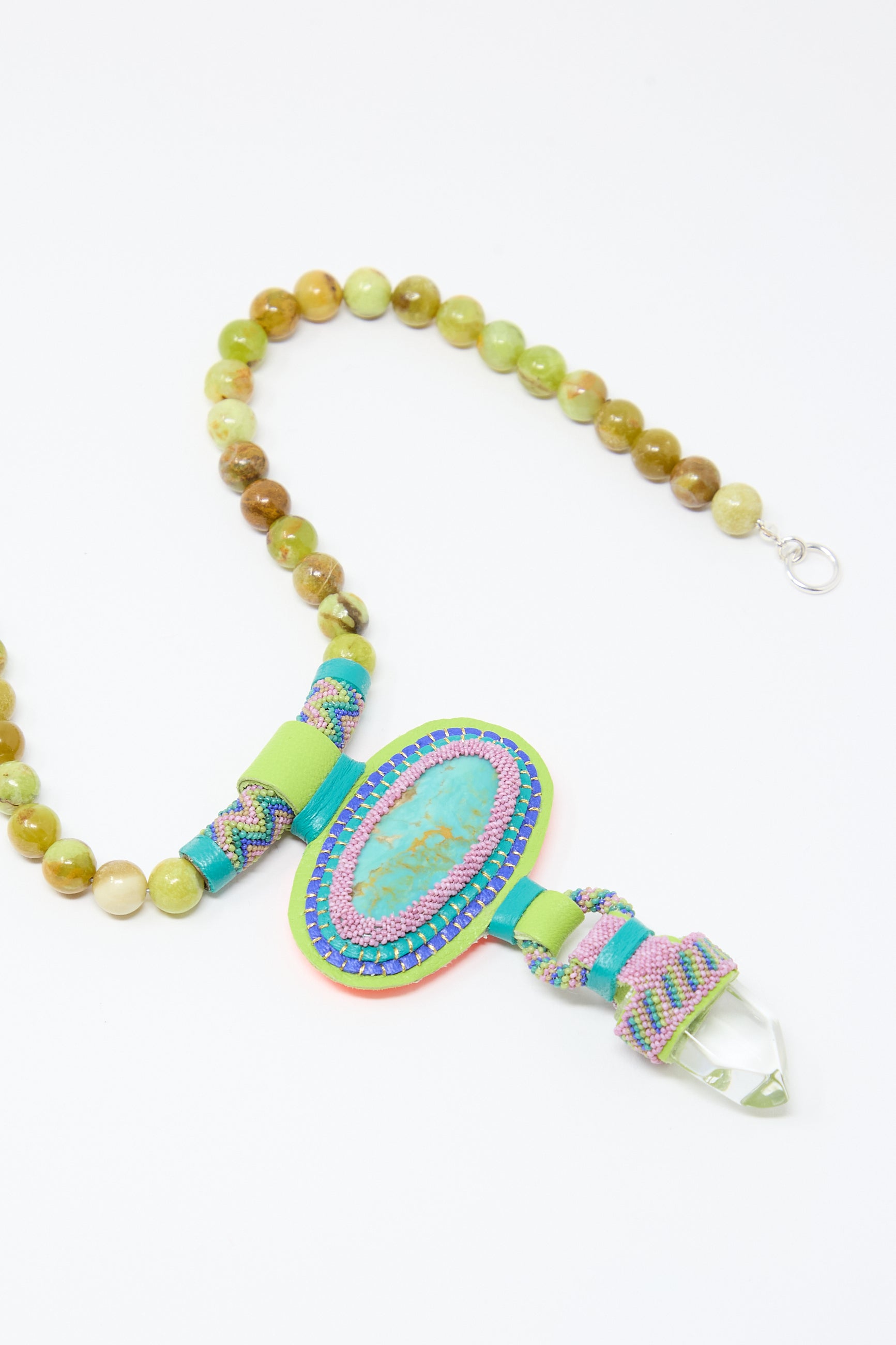 A Double Stone Necklace with Crystal, Olive Opal Beads and Turquoise Stone by Robin Mollicone, featuring a large multicolored oval pendant and a crystal at the end, elegantly complemented by turquoise stone accents.