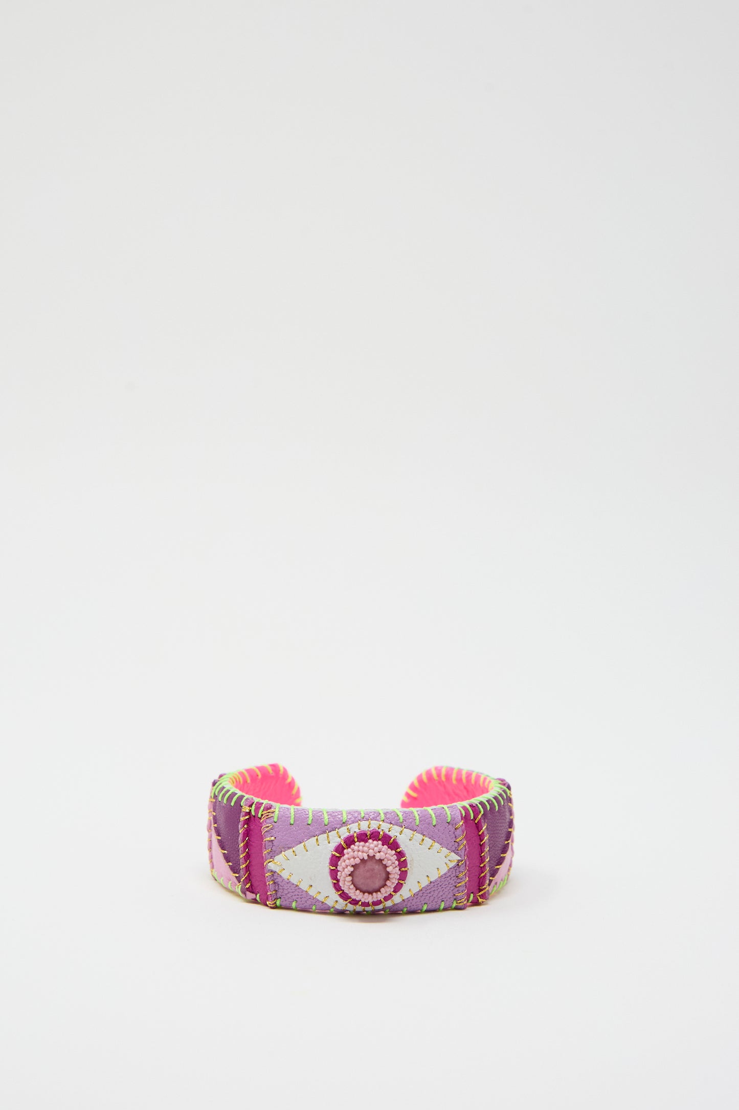 The Eye Cuff in Rhodonite by Robin Mollicone is a vibrant, hand-stitched leather accessory featuring a geometric design with pink, purple, and green stitching on a white background, crafted meticulously in New York.