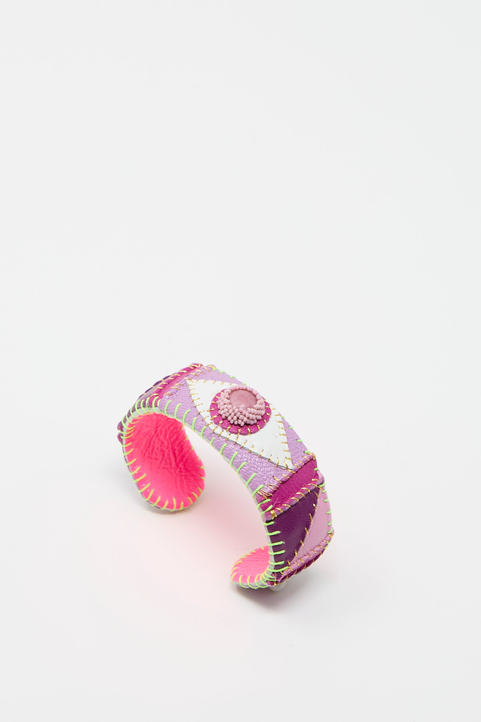 The Eye Cuff in Rhodonite by Robin Mollicone is a colorful hand-stitched leather cuff bracelet featuring pink, purple, and green stitching in a geometric design with a central pink button, handmade in New York.