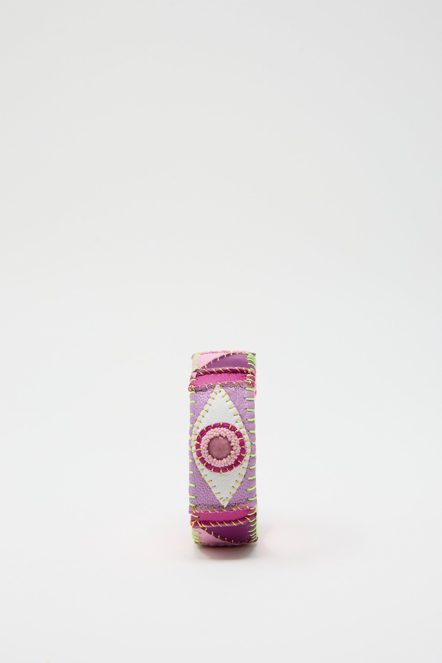 Introducing the Eye Cuff in Rhodonite by Robin Mollicone, a vibrant fabric bracelet featuring intricate geometric patterns in shades of pink, purple, and white, expertly handmade in New York.