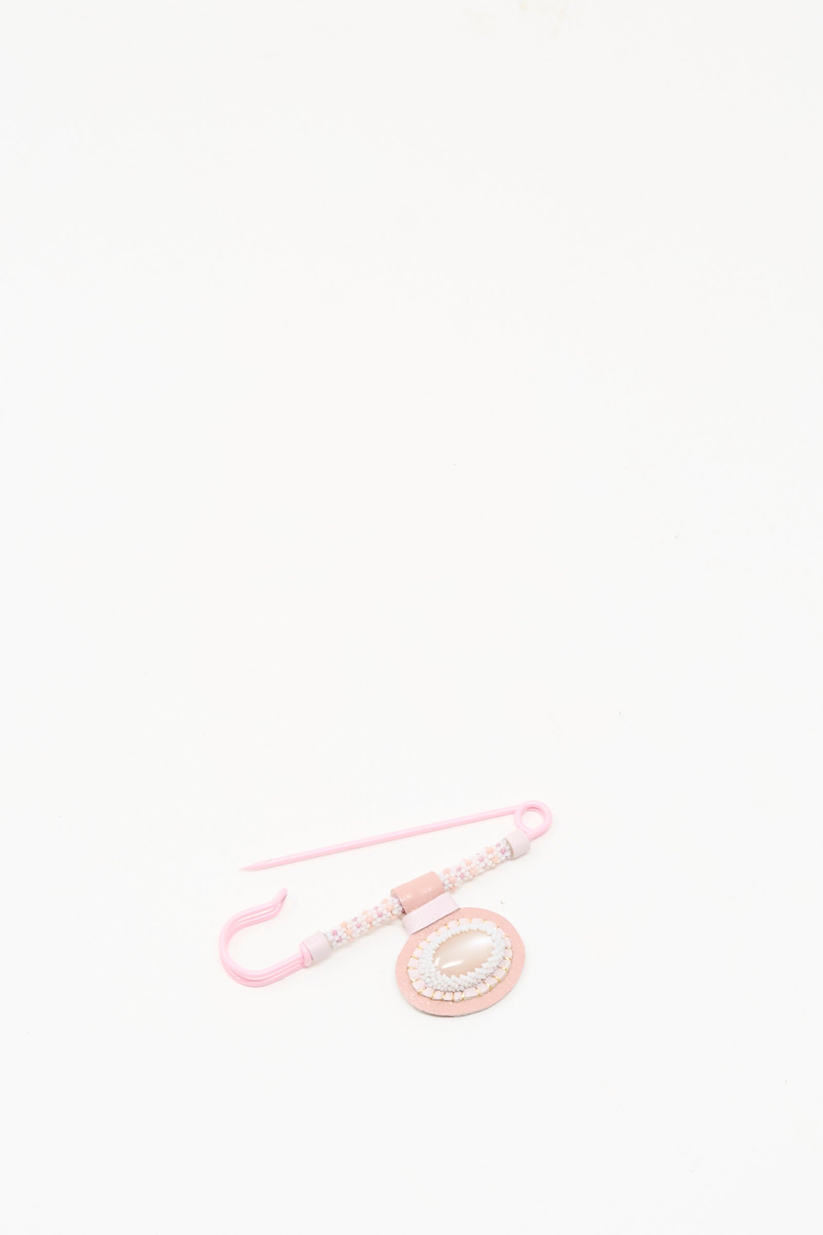 The Robin Mollicone Gem Drop Brooch in Pink Moonstone, handmade in NYC, is displayed on a plain white surface alongside a matching beaded spiral accessory.