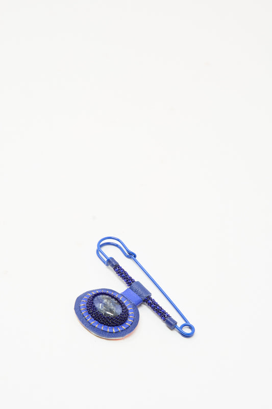 Handmade in New York, this Gem Drop Safety Pin in Blue Sodalite features a sodalite cabochon pendant framed by dark blue seed beads in a beaded brooch design.