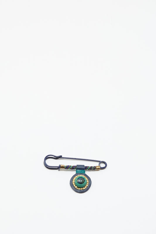 The Robin Mollicone Gem Drop Safety Pin in Blue with Azurite features antique glass beads and a green circular ornament, displayed on a white background.