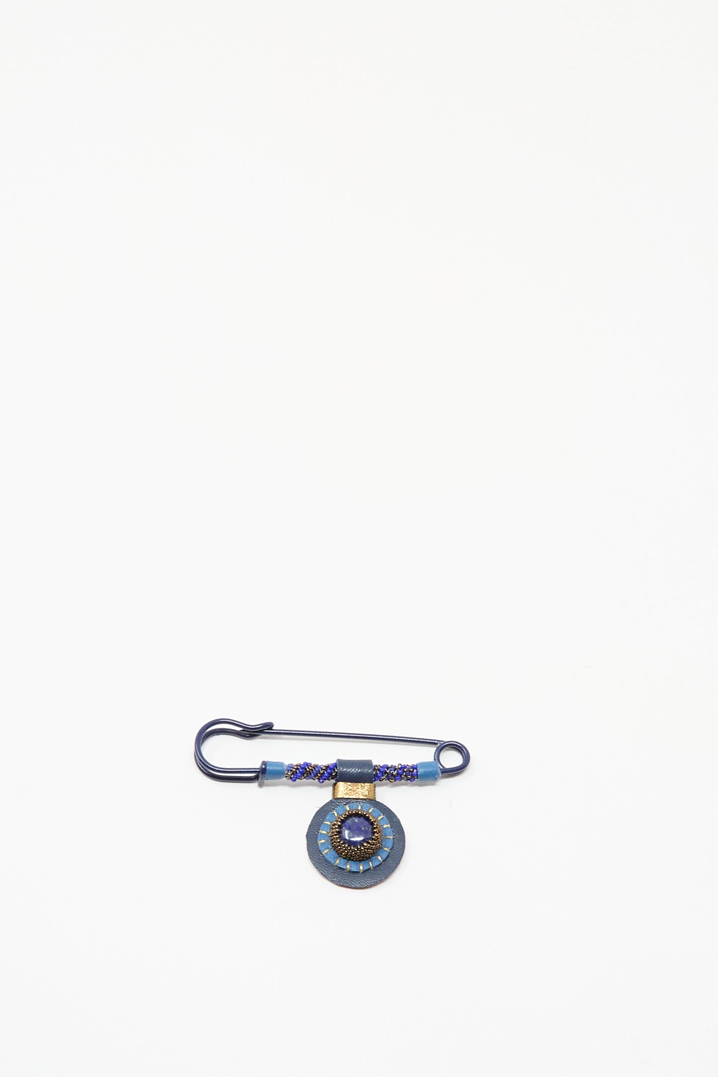 The Gem Drop Safety Pin in Lapis by Robin Mollicone is a handmade dark blue beaded pin from NYC, featuring a round lapis-detailed pendant, shown on a plain white background.