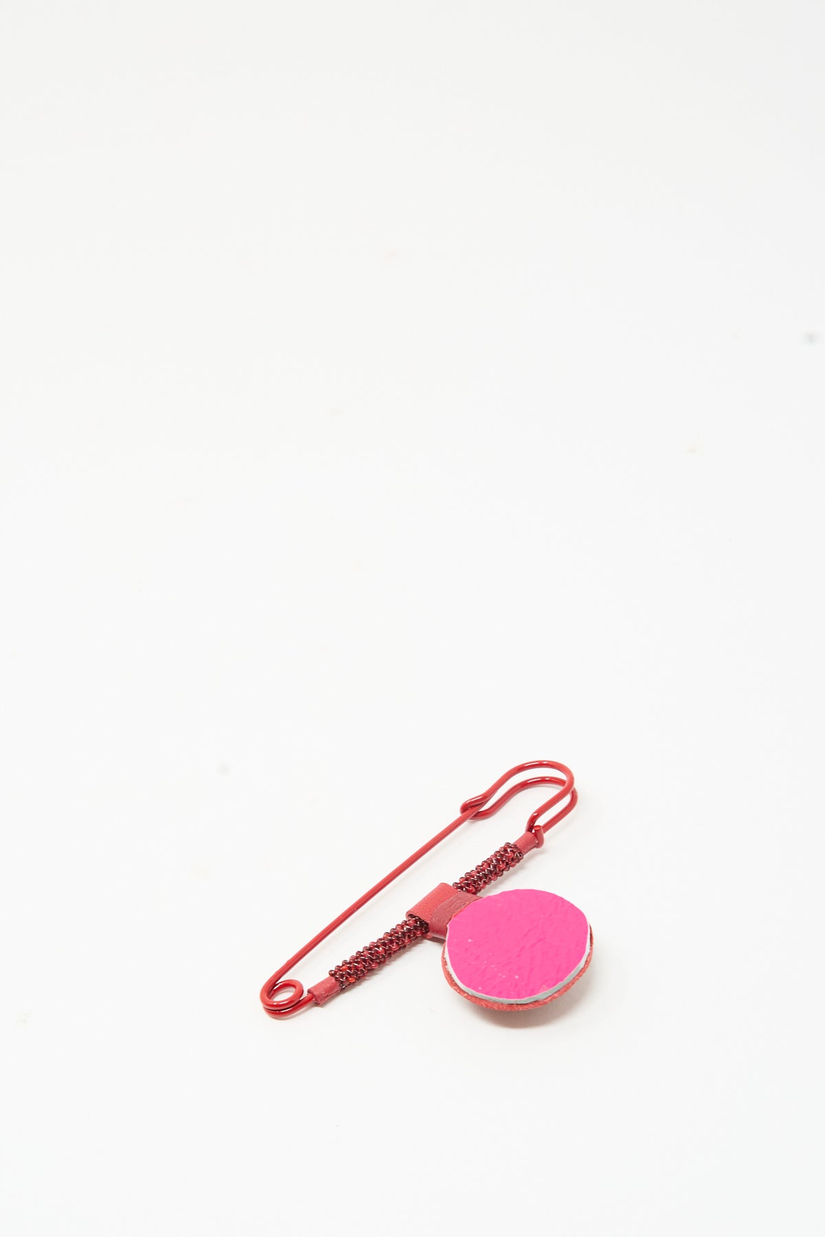 A red Gem Safety Pin in Red Carnelian adorned with a flat, circular, hot-pink decorative element, captured in this handmade in New York beaded brooch.