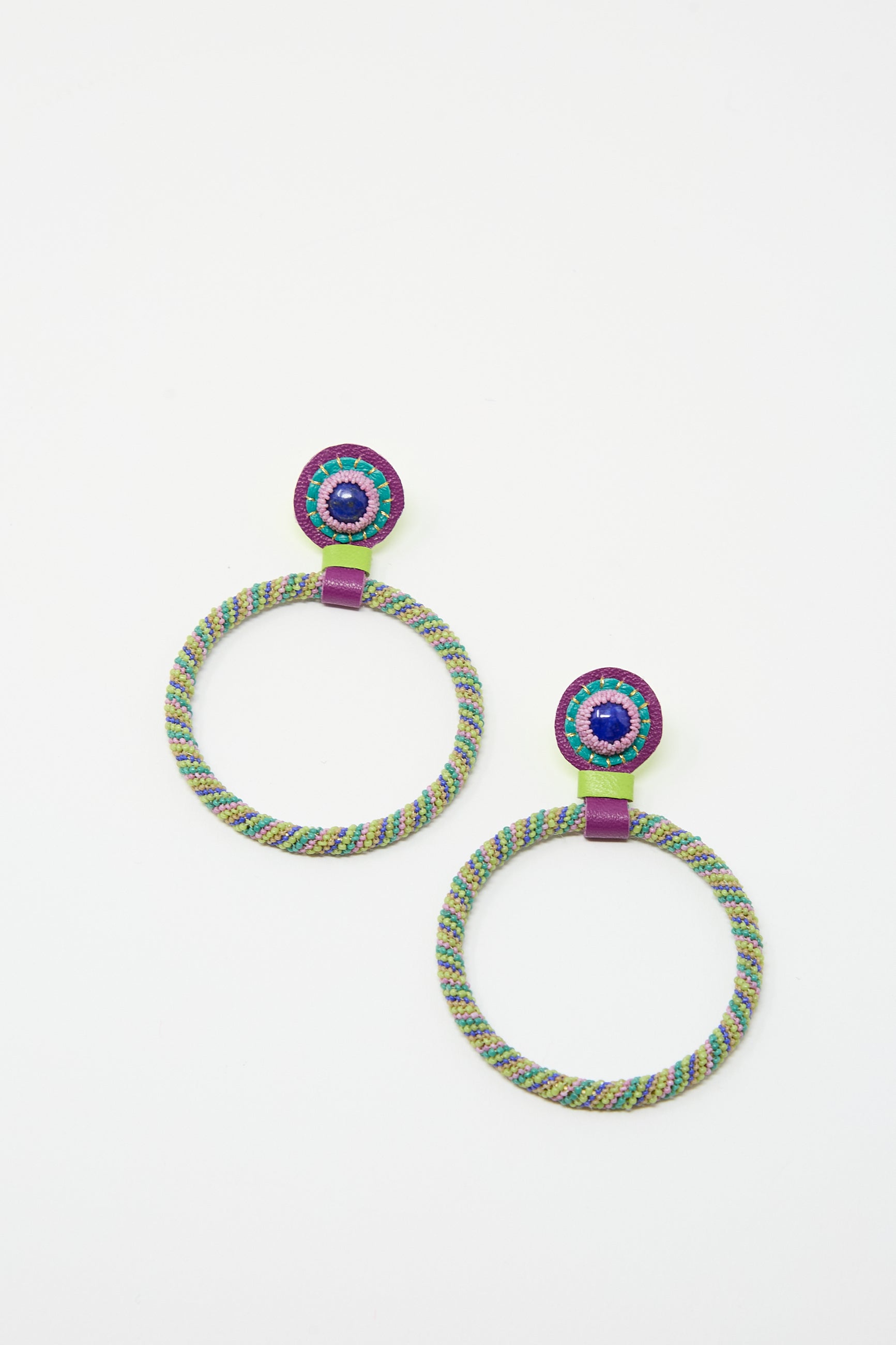 Close-up of a pair of colorful, circular Robin Mollicone Large Beaded Hoop Earrings in Multi Spiral with Lapis Stone Tops with braided rope design, beaded centers, and sterling silver posts on a plain white background.