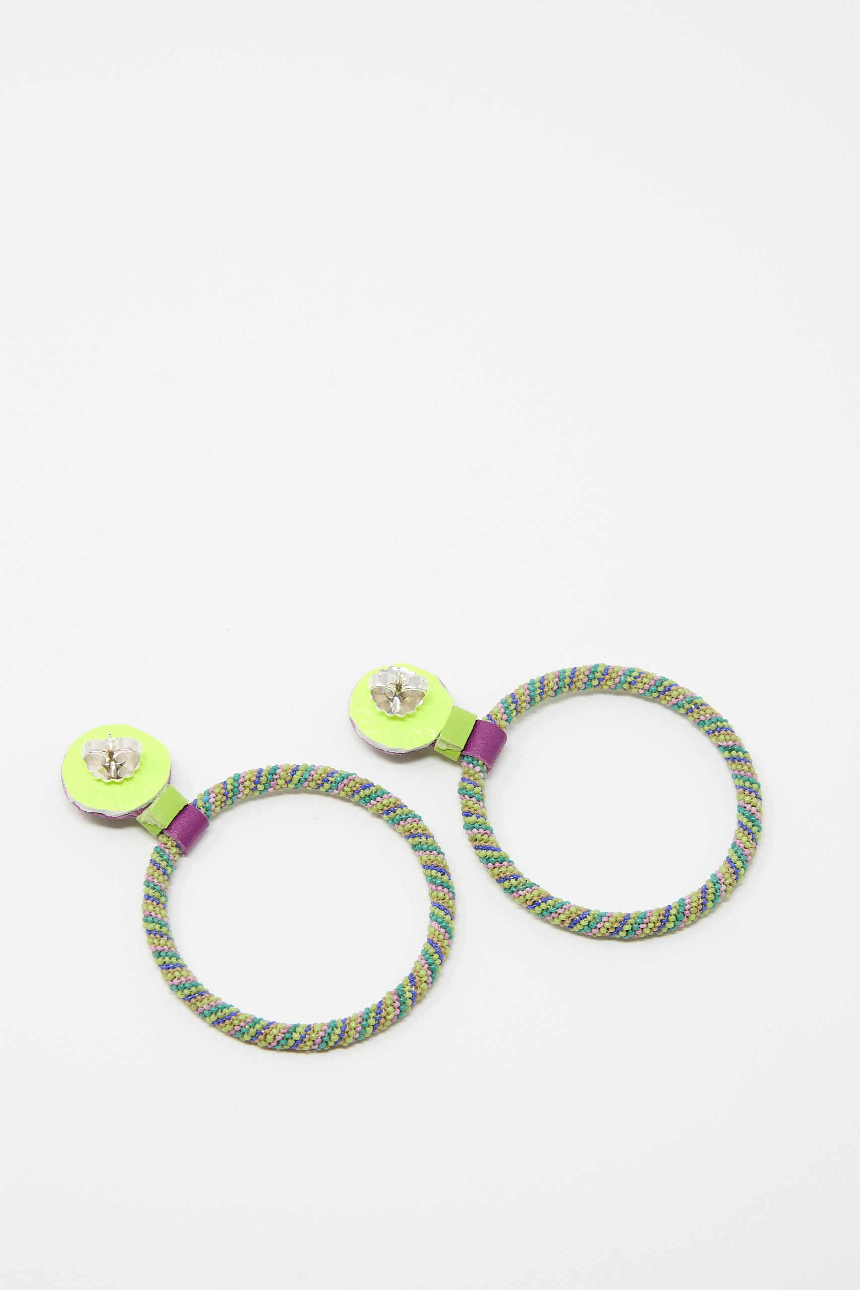 Two colorful round earrings with a multicolored woven design, neon green accents, and clear gemstone details on a white background, featuring sterling silver posts. These are the Large Beaded Hoop Earrings in Multi Spiral with Lapis Stone Tops by Robin Mollicone.