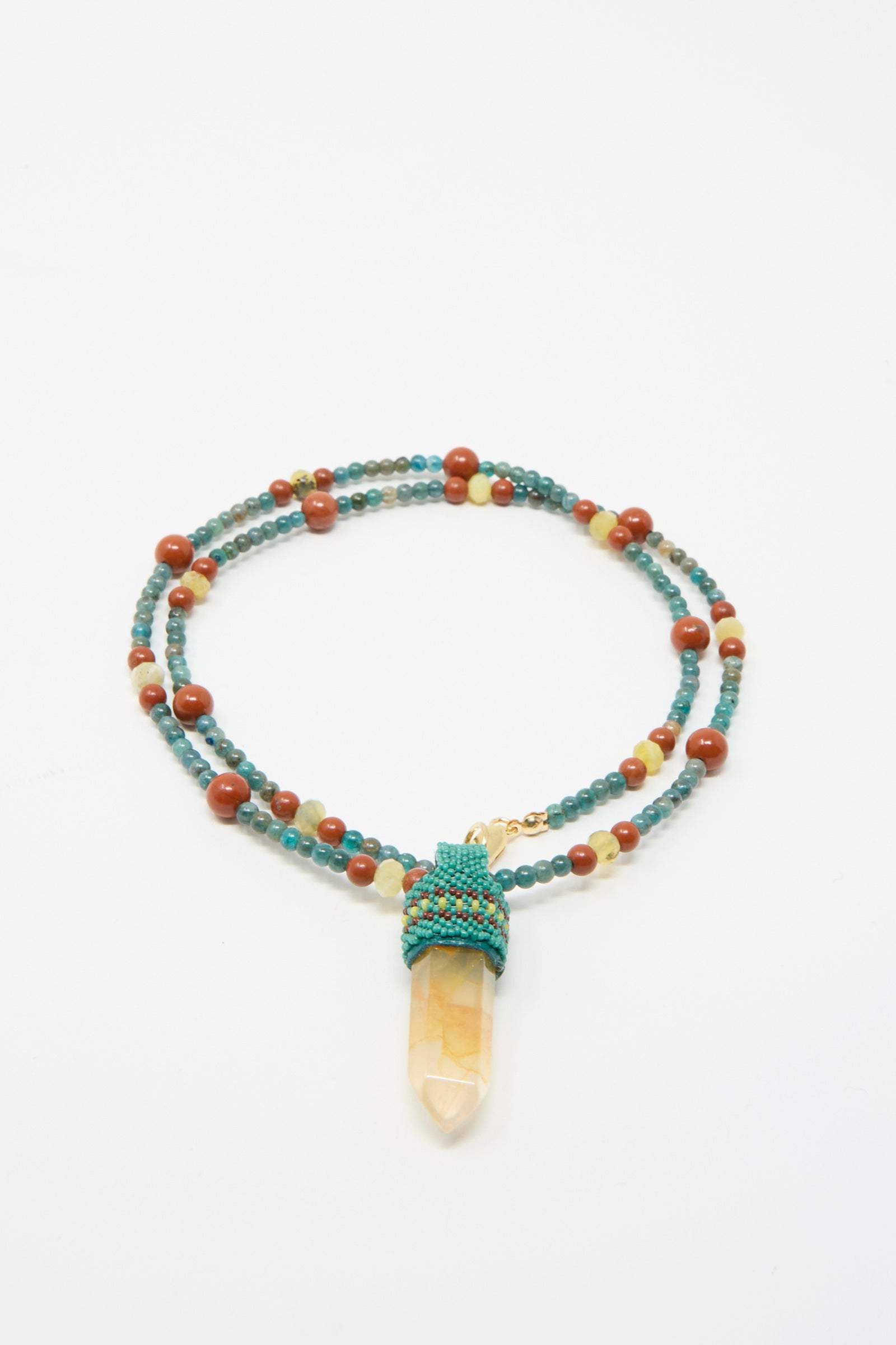 A Long Pendulum Necklace in Apatite with Red Jasper, Olive Opal beads, and Quartz crystal pendant by Robin Mollicone, displayed on a plain white background.