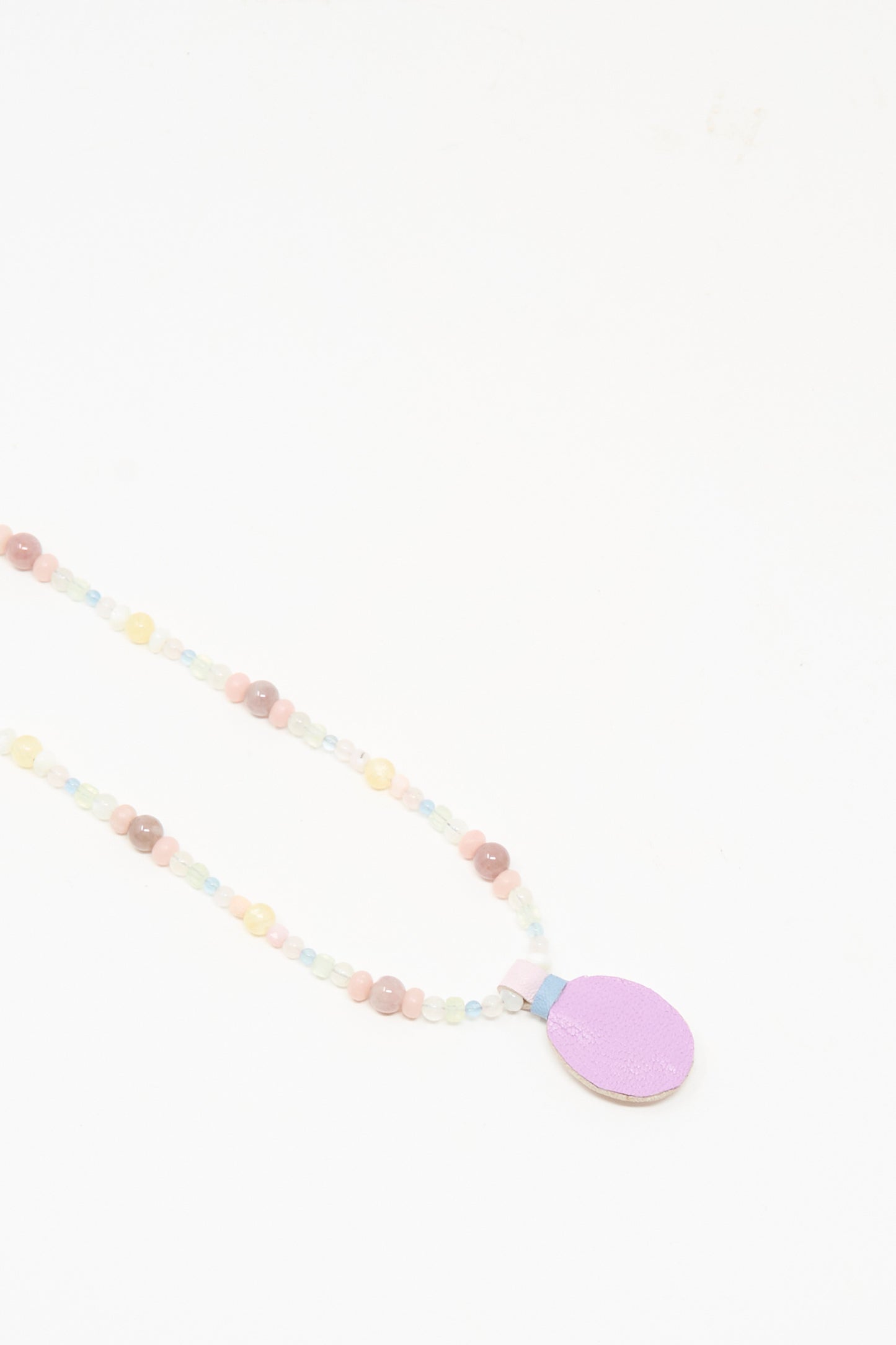 The Robin Mollicone Love Bead Charm Necklace in Pink Moonstone showcases pastel vintage glass beads and a flat, oval lavender pendant, displayed against a white background.