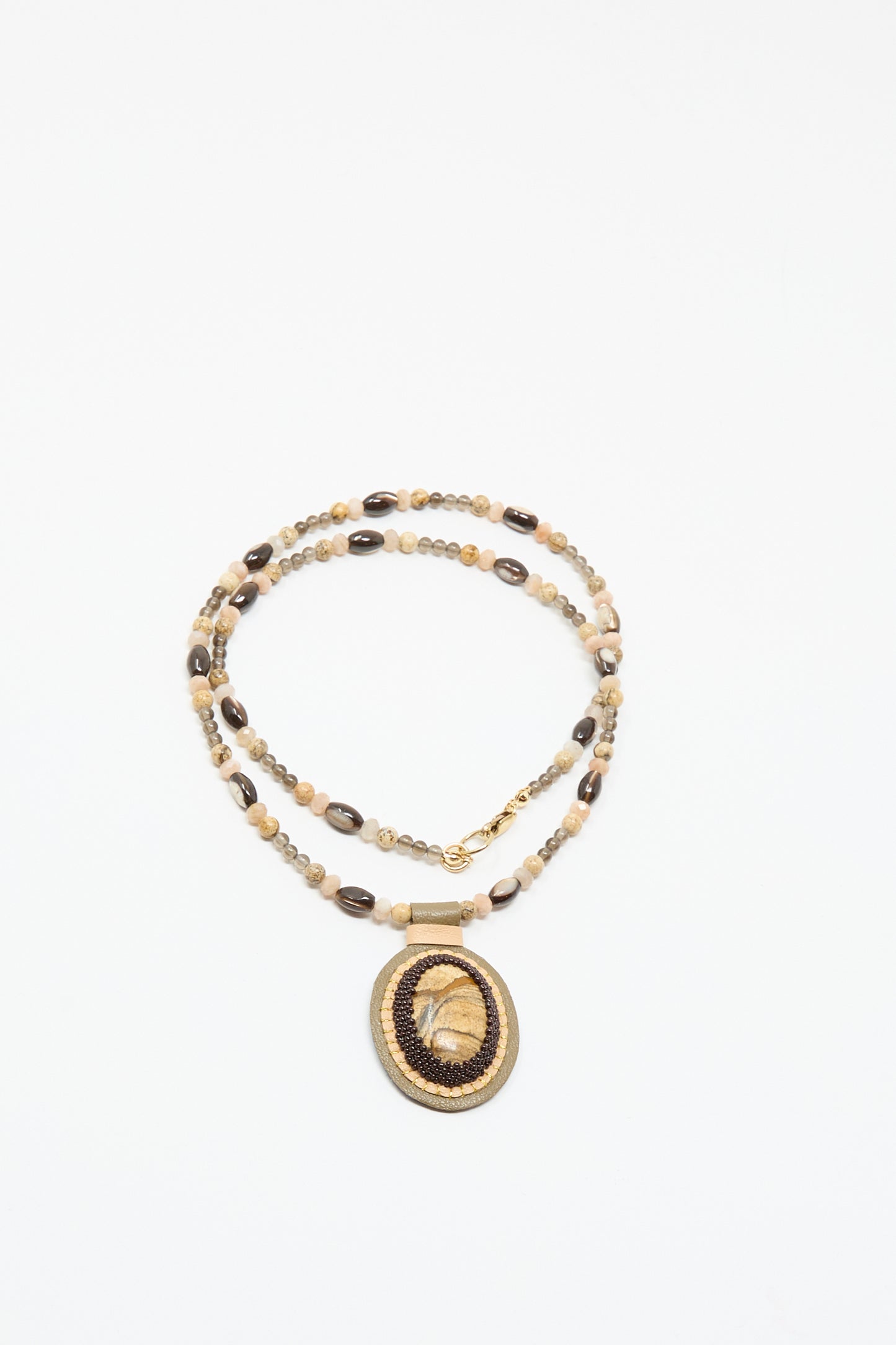 The Robin Mollicone Love Bead Necklace in Brown features beige and brown beads with a round, woven picture jasper spiral charm, shown on a white background.