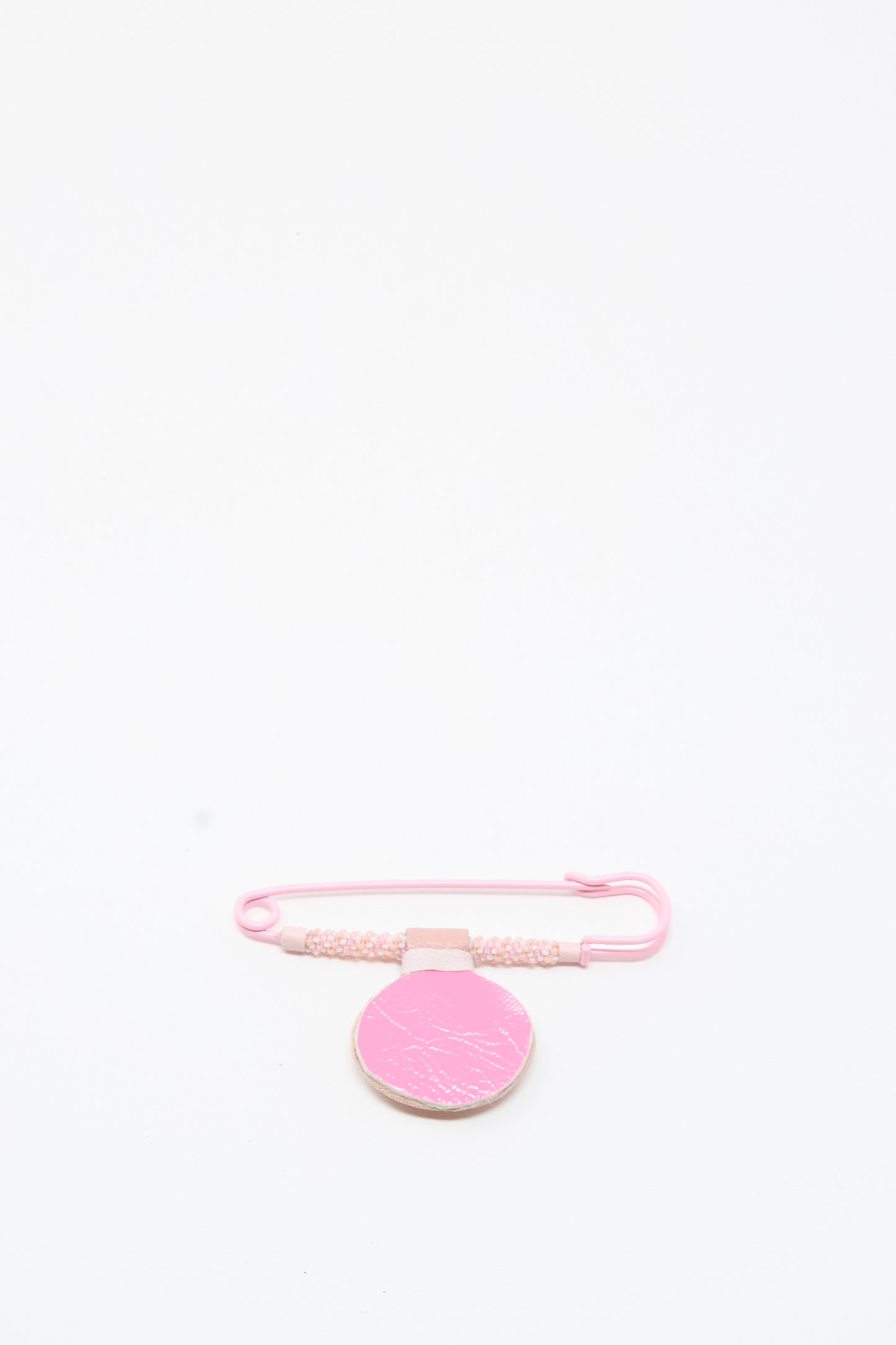 The Moonstone Gem Drop Brooch in Pink by Robin Mollicone is displayed on a plain white background, featuring delicate beaded safety pin detailing and a textured, circular pink tag—all handmade in NYC.