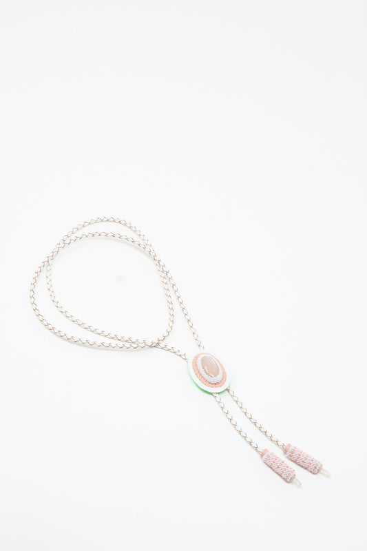The Robin Mollicone Moonstone, Quartz Bolo Necklace in Pink and White features a handmade braided design with an oval pink moonstone centerpiece and two pink cylindrical tips, displayed on a white background.