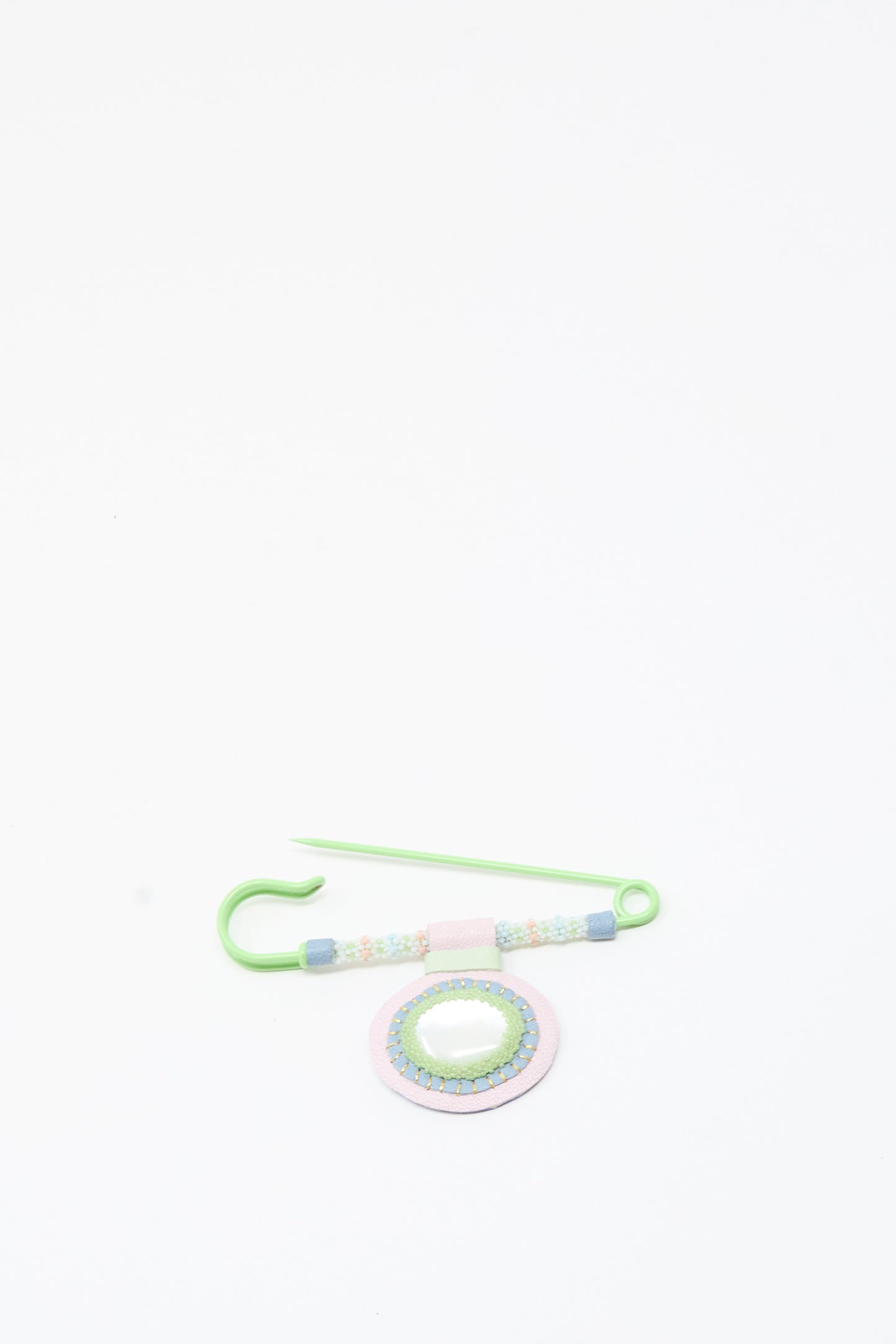 A green Mother of Pearl Gem Drop Brooch by Robin Mollicone, handmade in NYC with decorative beads and a circular beaded ornament featuring Mother of Pearl accents, is displayed on a white background.