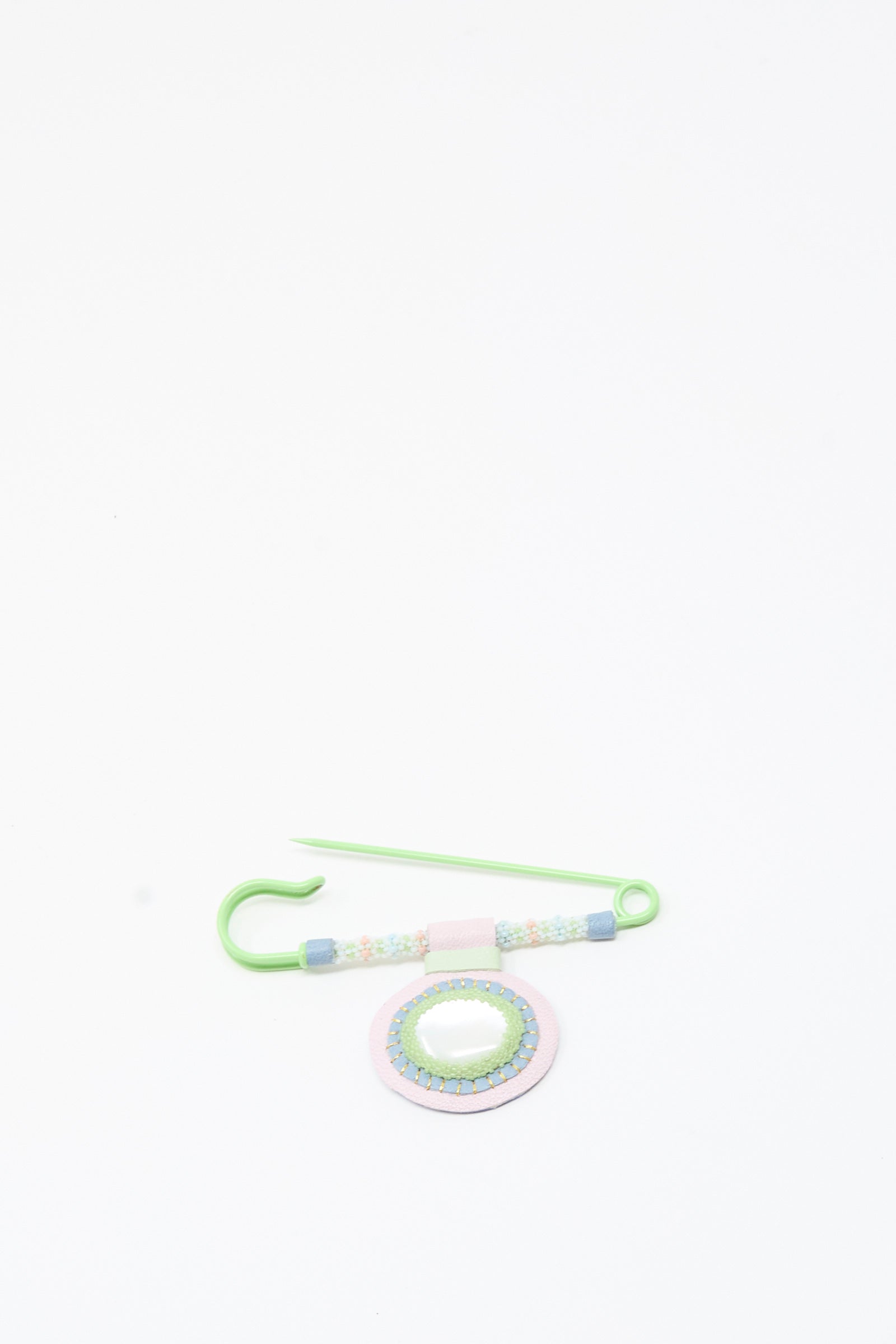 A green Mother of Pearl Gem Drop Brooch by Robin Mollicone, handmade in NYC with decorative beads and a circular beaded ornament featuring Mother of Pearl accents, is displayed on a white background.