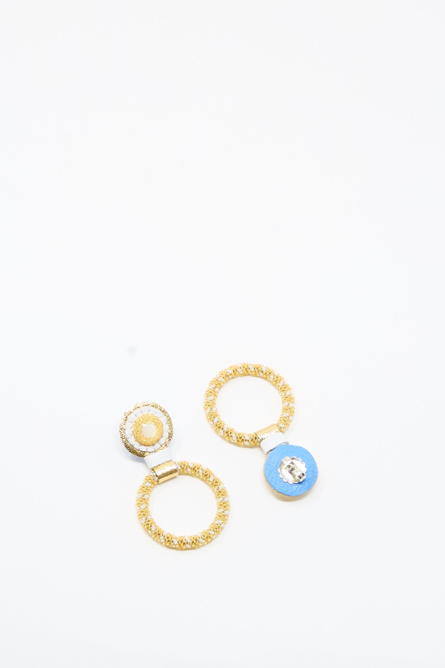 Displayed on a white background are three gold rings: one with a center resembling the pearl detail of Robin Mollicone's Mother of Pearl Small Beaded Hoop Earrings in Pearl and Gold, another with a blue gem centerpiece, and the third featuring a yellow center.