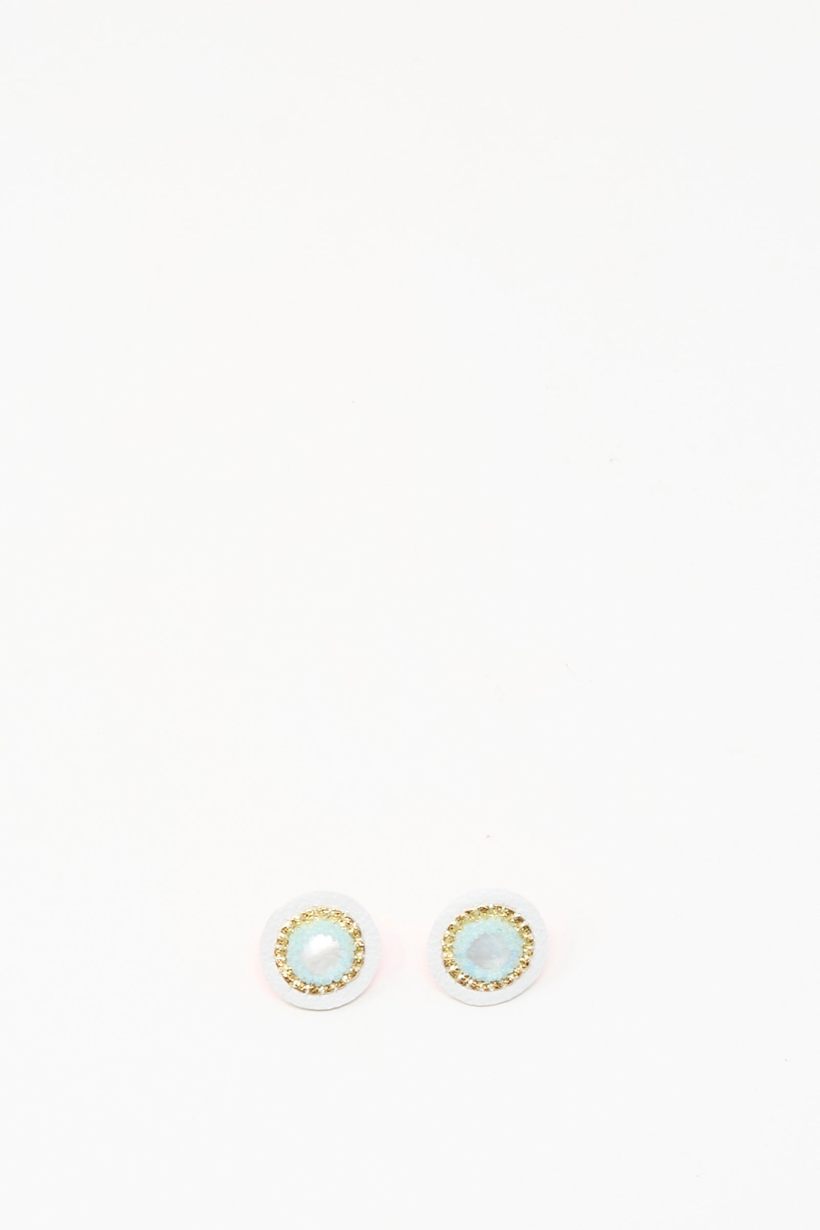 Robin Mollicone Stud Earrings in Mother of Pearl feature light blue stones at the center, encircled by a gold-colored border, and are shown on a white background.