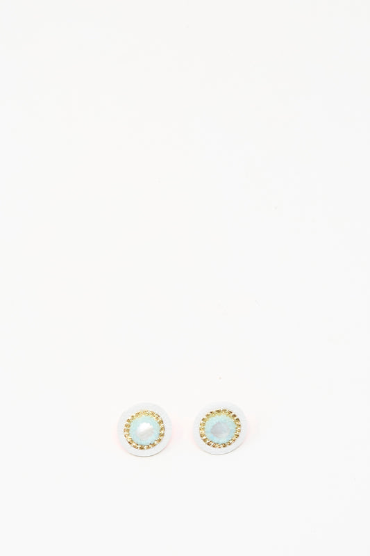 Robin Mollicone Stud Earrings in Mother of Pearl feature light blue stones at the center, encircled by a gold-colored border, and are shown on a white background.