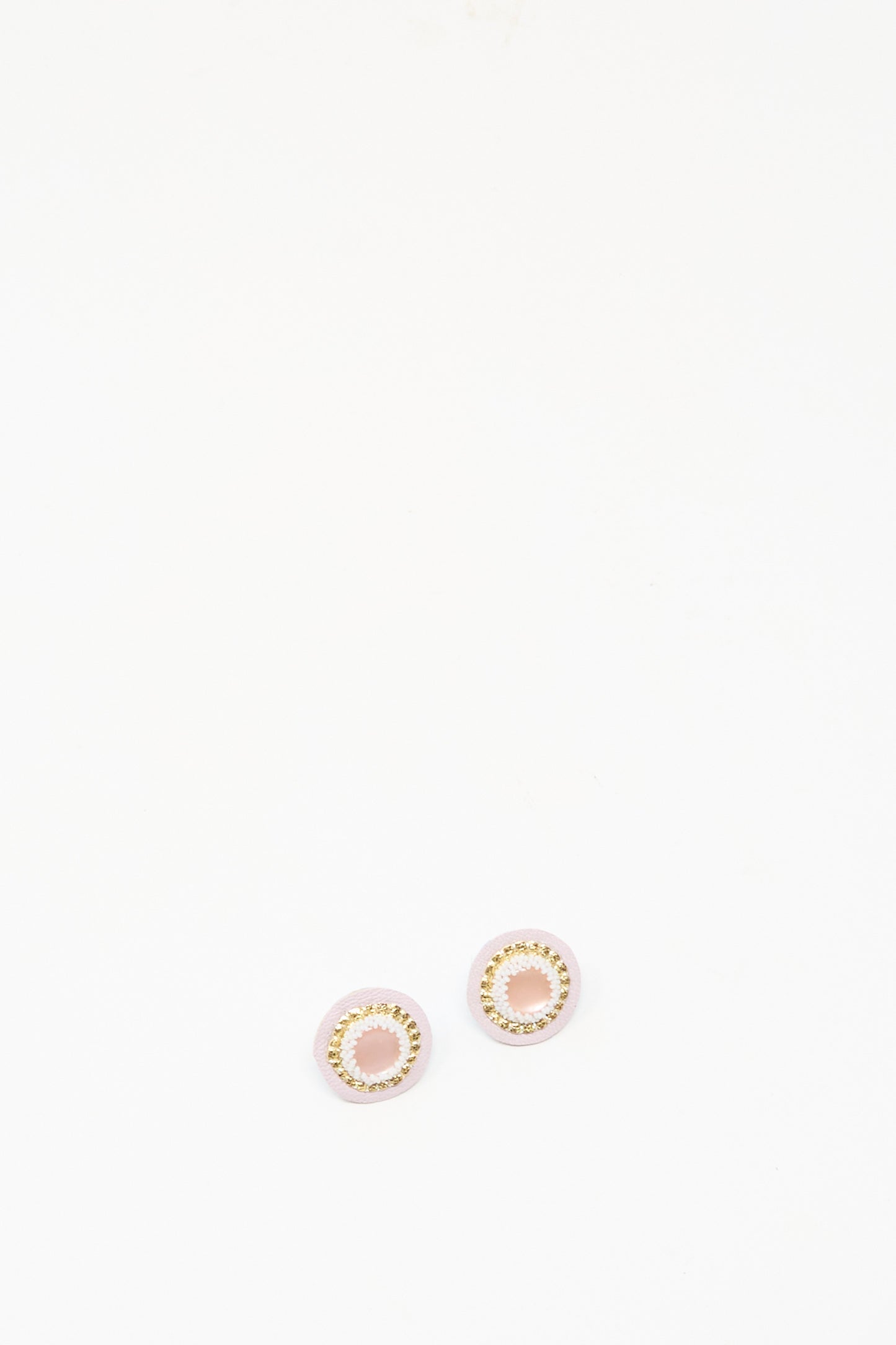 The Robin Mollicone Mother of Pearl Stud Earrings in Pink are small, round handmade studs with a gold circular design set on a plain white background.