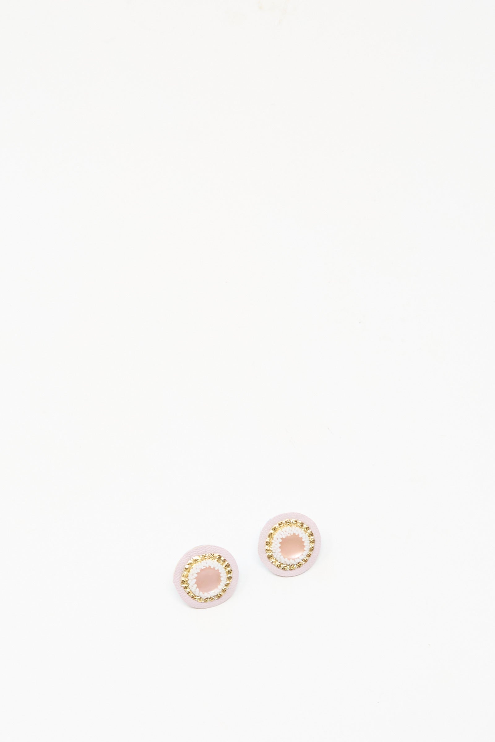The Robin Mollicone Mother of Pearl Stud Earrings in Pink are small, round handmade studs with a gold circular design set on a plain white background.