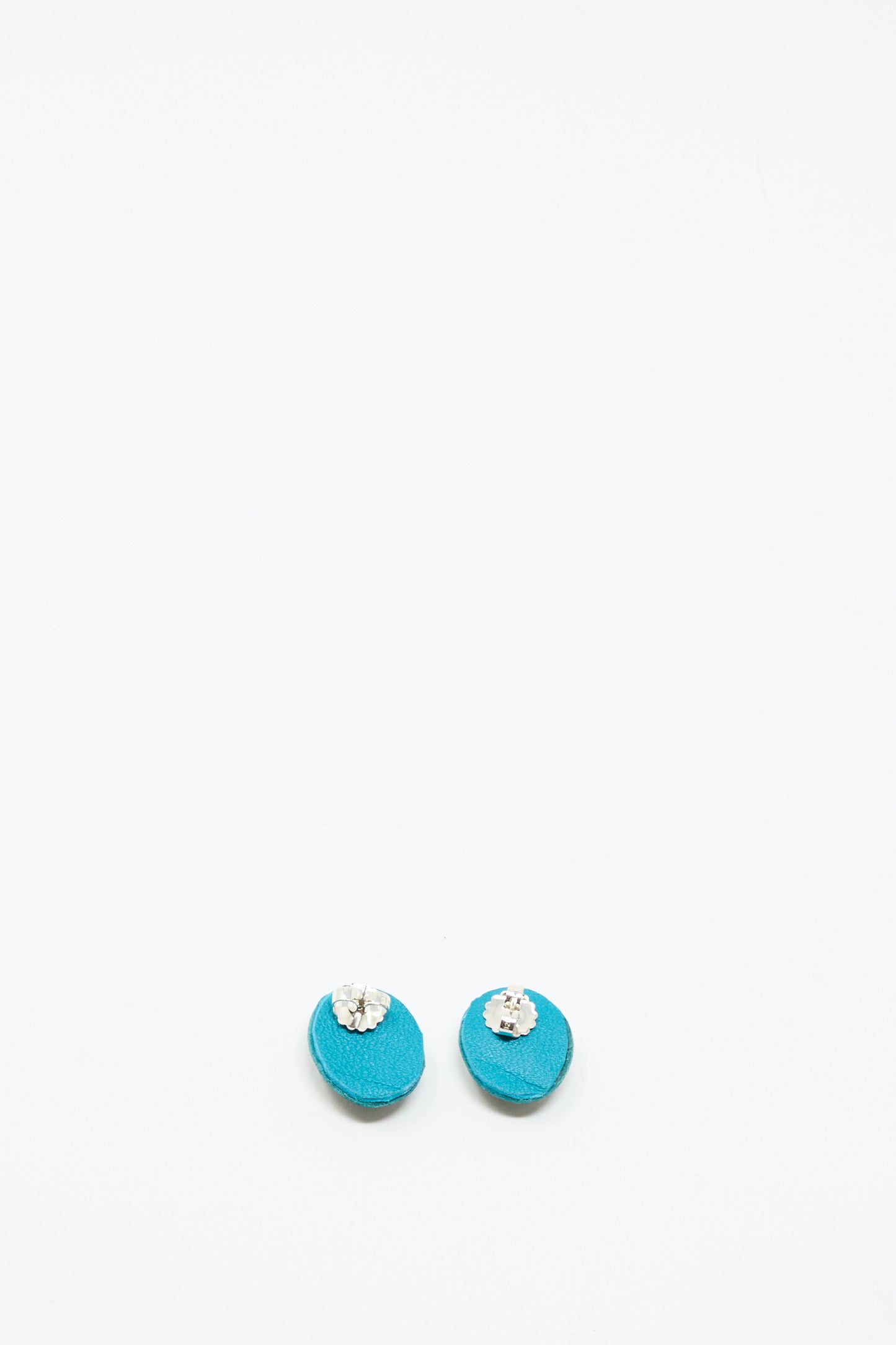 The Oval Earrings in Apatite by Robin Mollicone feature turquoise hues with small silver or clear gemstone accents, shown against a plain white background.