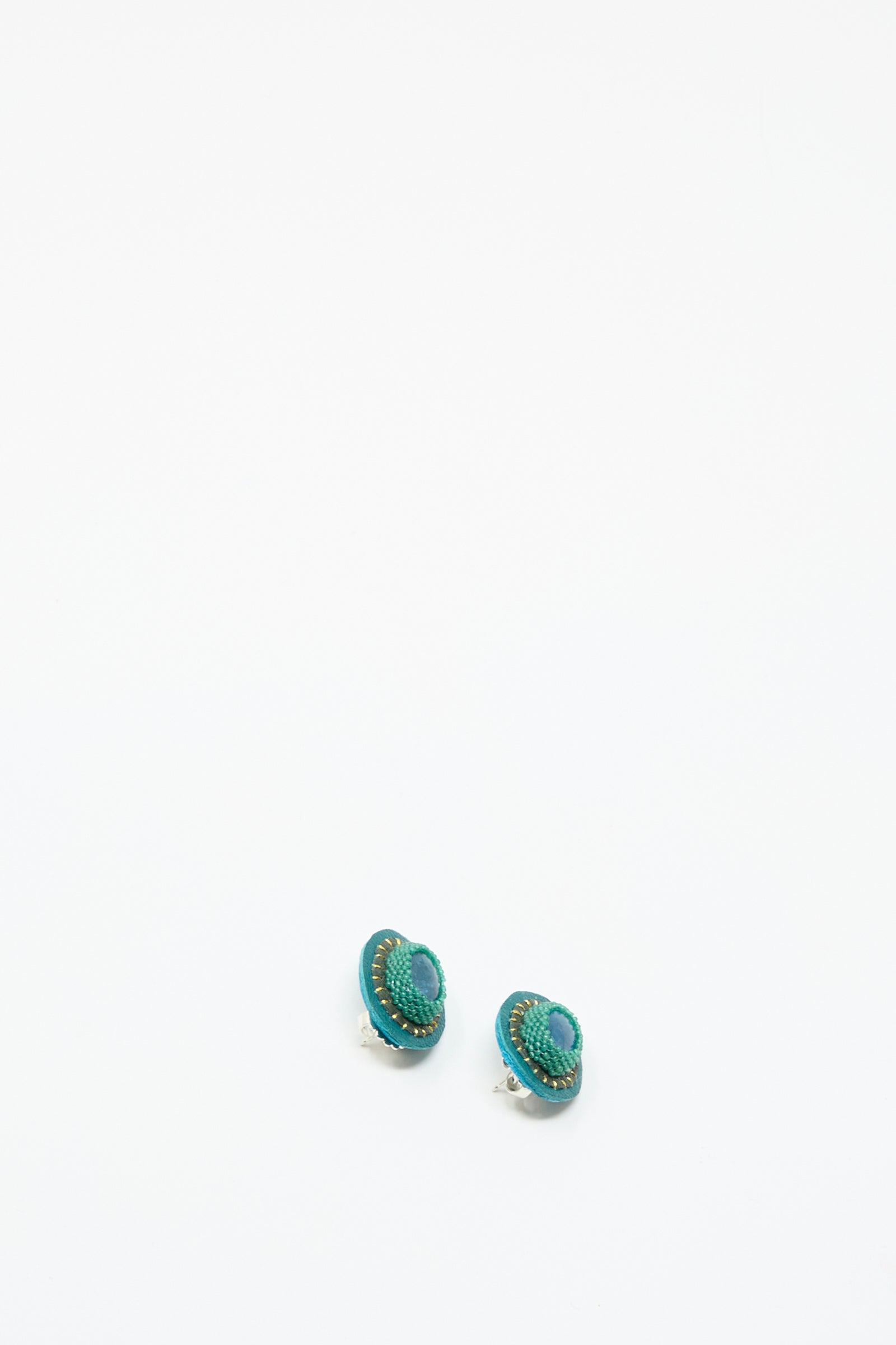 A pair of small, oval, teal and green handmade Robin Mollicone "Oval Earrings in Apatite" featuring a textured pattern, shown on a plain white background.