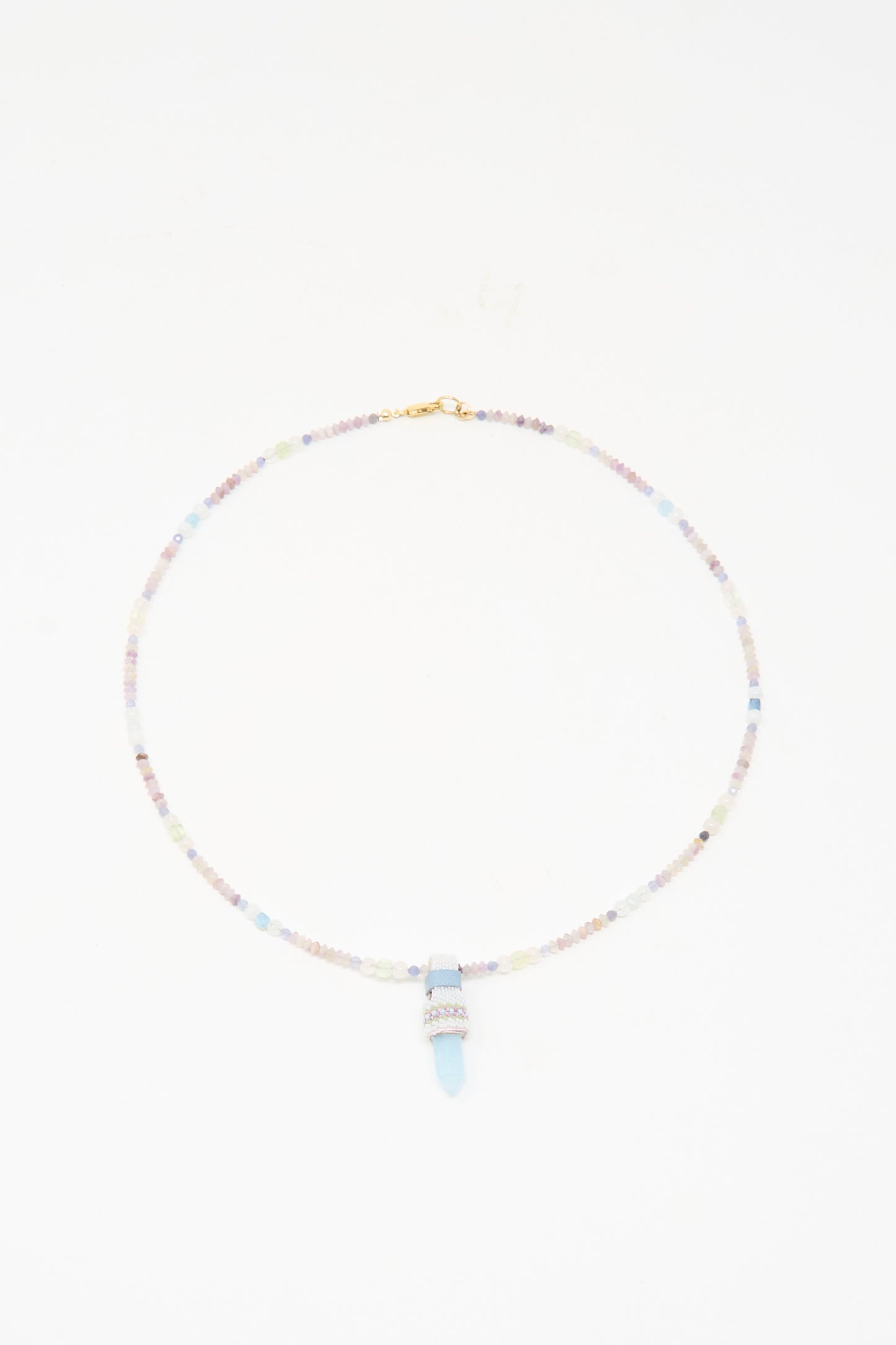 The Peace of Mind Necklace in Aquamarine by Robin Mollicone features pastel beads and a light blue quartz crystal pendant, shown against a white background.