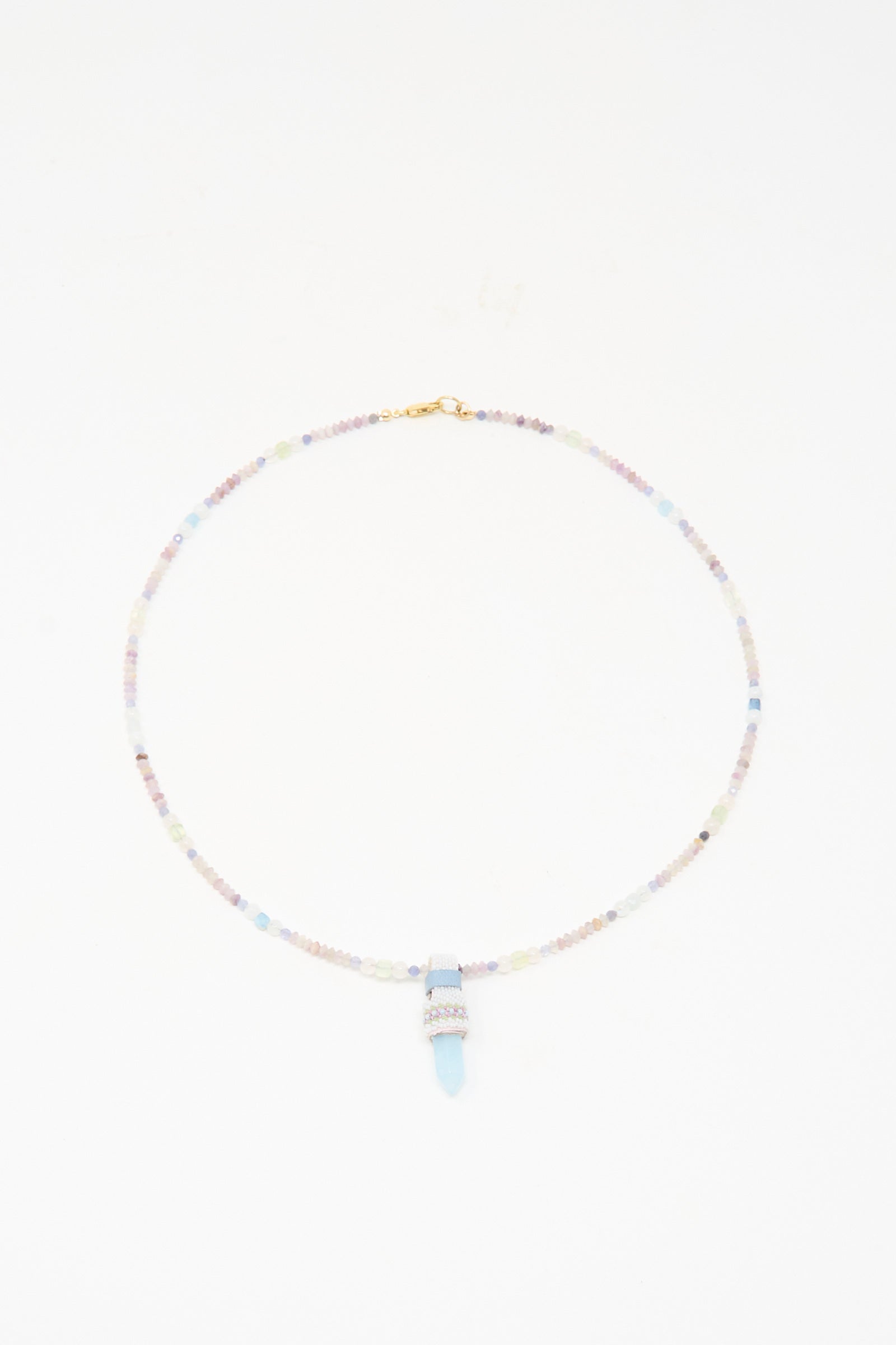 The Peace of Mind Necklace in Aquamarine by Robin Mollicone features pastel beads and a light blue quartz crystal pendant, shown against a white background.