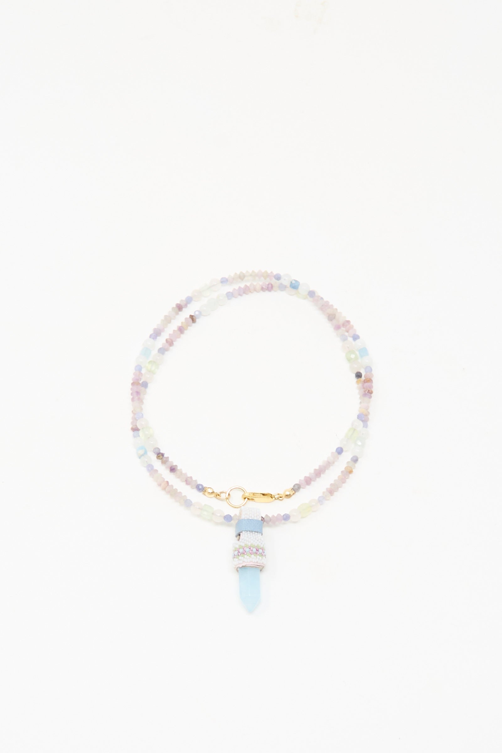 The Peace of Mind Necklace in Aquamarine by Robin Mollicone features pastel beads, a gold clasp, and an aquamarine pendant, presented against a white background.