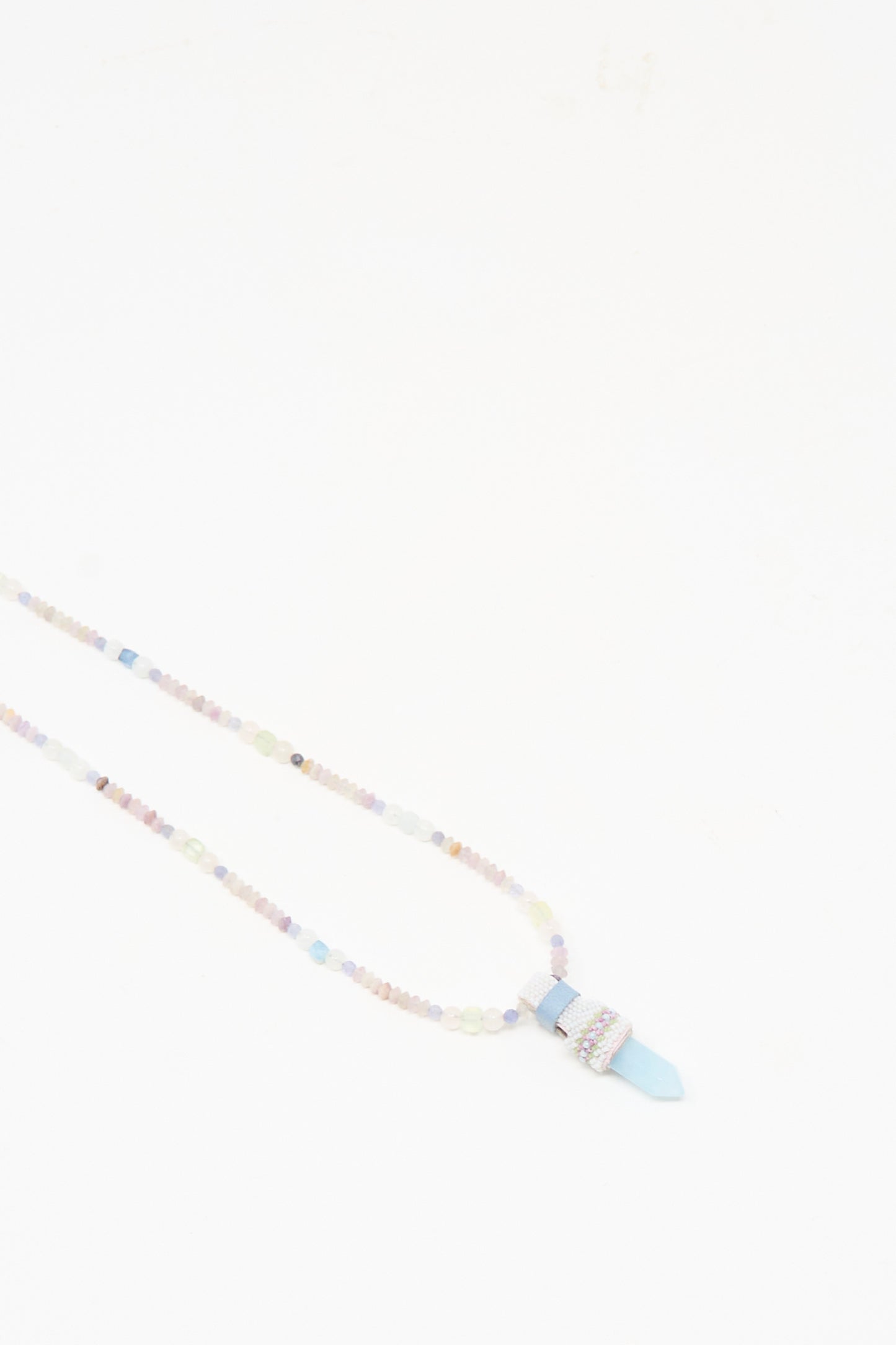 The Peace of Mind Necklace in Aquamarine by Robin Mollicone features pastel beads and a blue quartz crystal pendant, shown against a plain white background.