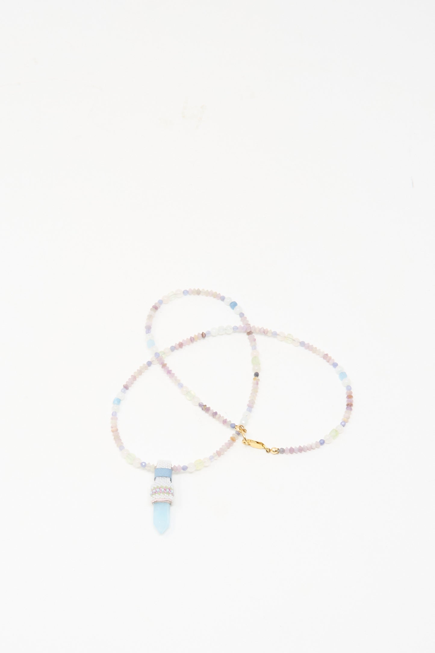 The Peace of Mind Necklace in Aquamarine by Robin Mollicone features pastel beads and a light blue quartz crystal pendant, beautifully displayed on a white background.