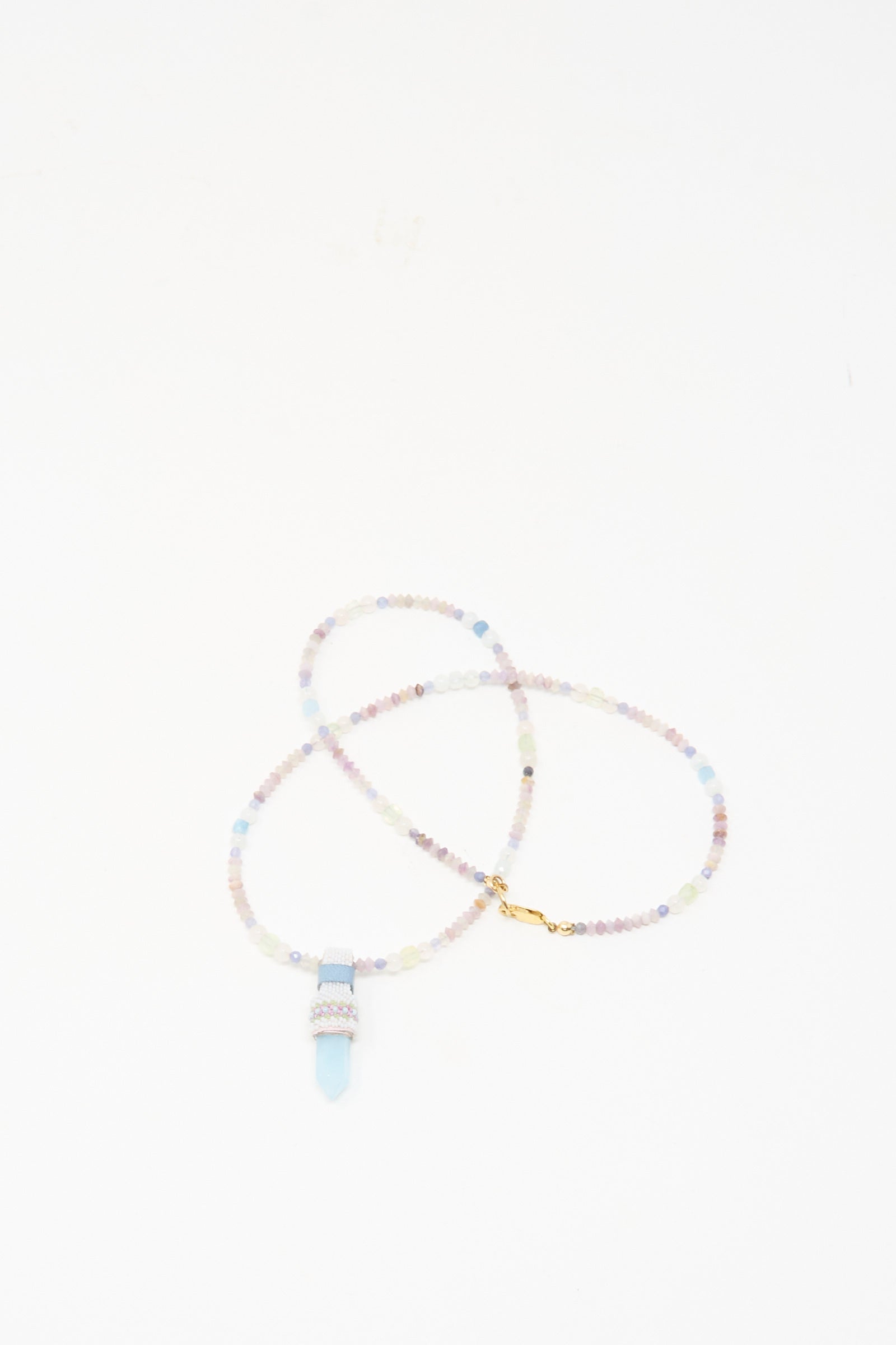 The Peace of Mind Necklace in Aquamarine by Robin Mollicone features pastel beads and a light blue quartz crystal pendant, beautifully displayed on a white background.