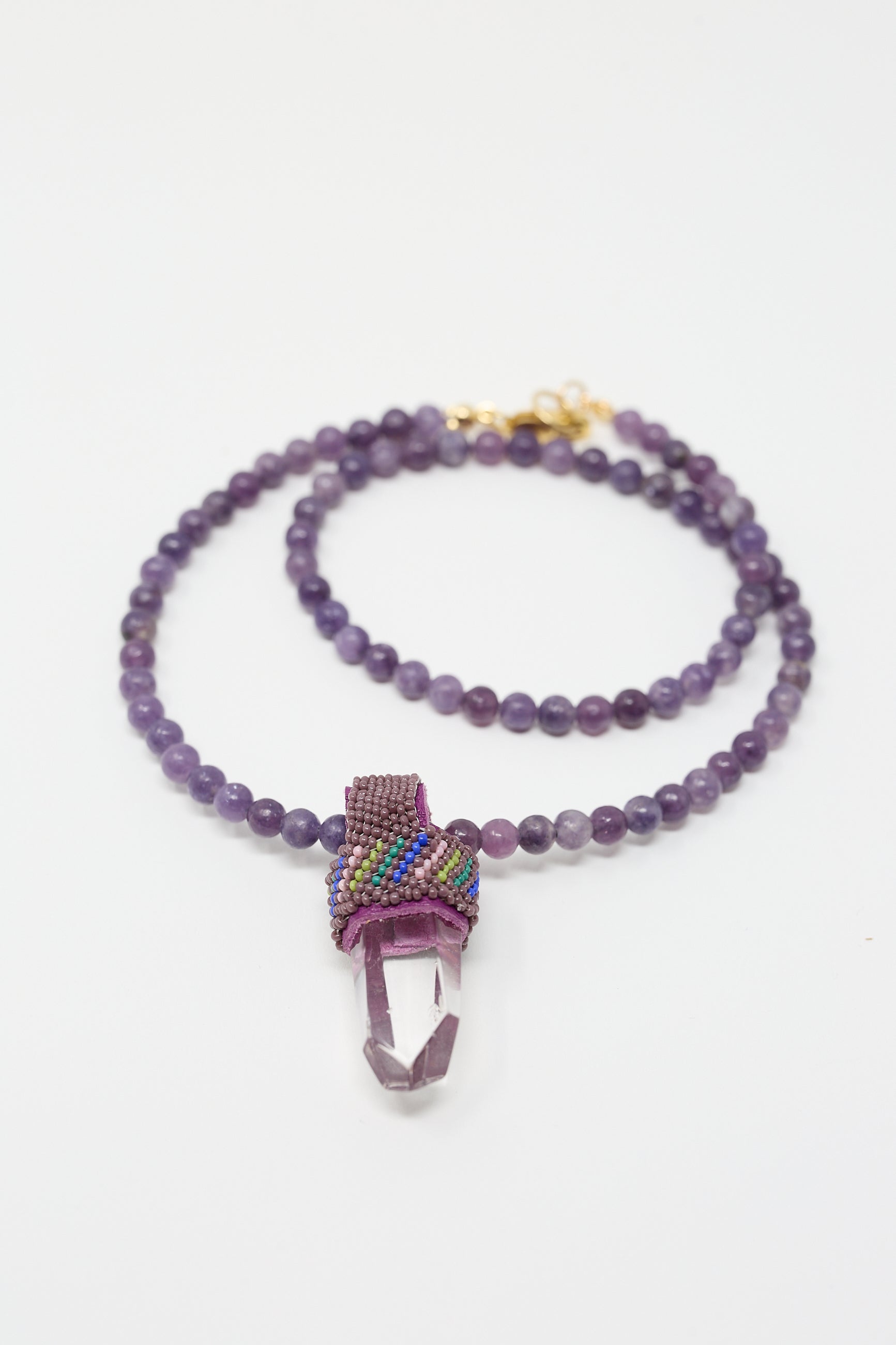 A handmade Robin Mollicone Pendulum Necklace in Round Lepidite Beads and Quartz Crystal featuring a gold clasp, highlighted by a colorful beaded section near the pendant.