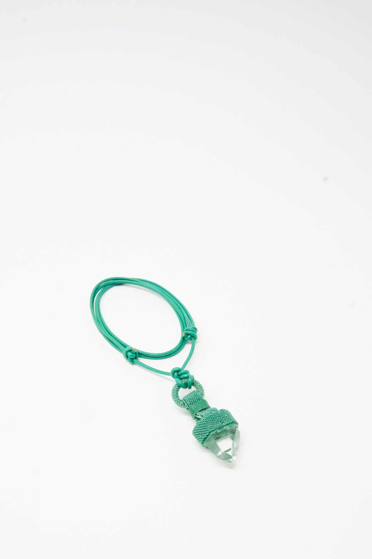 Robin Mollicone Quartz Crystal Pendulum Necklace in Green featuring a clear quartz crystal point pendant in a green woven cord setting on a matching adjustable green leather necklace.