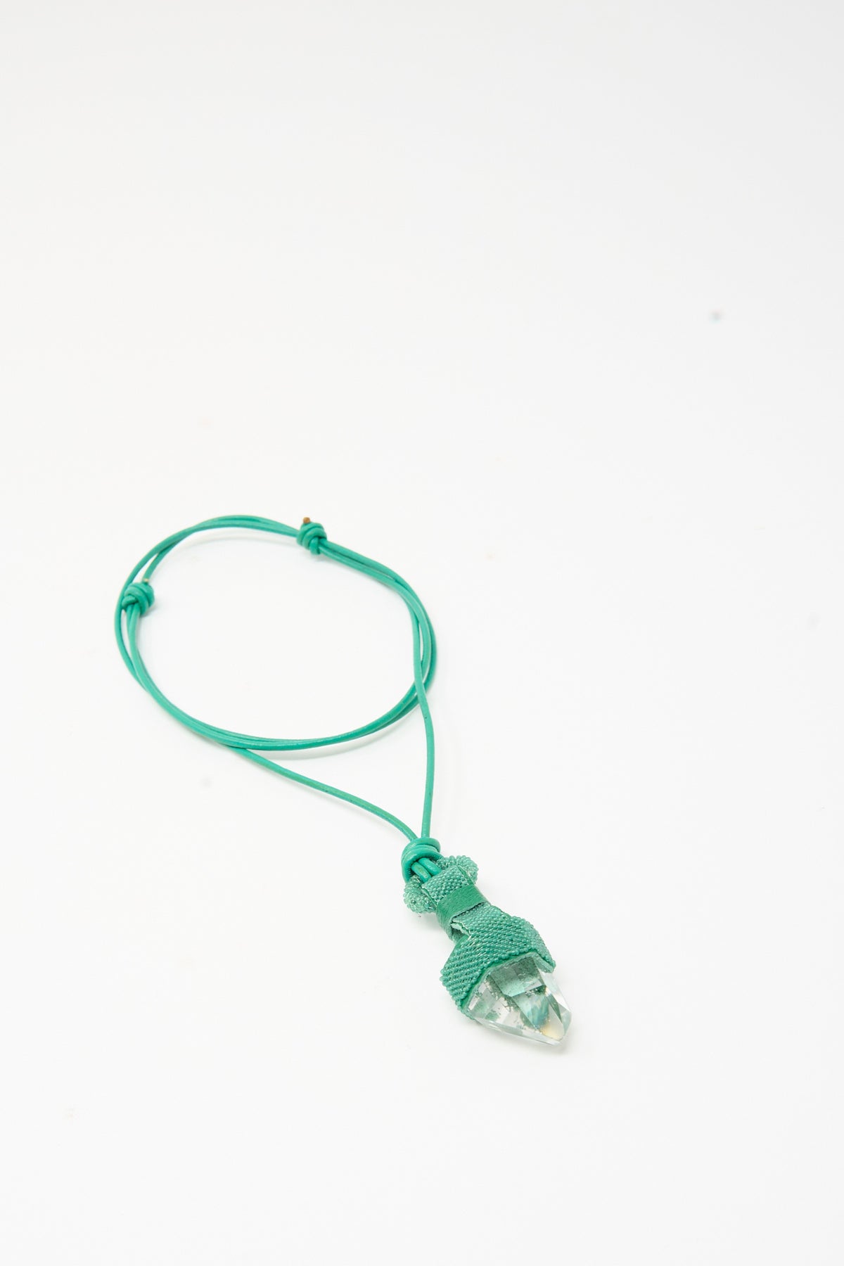 Robin Mollicone Quartz Crystal Pendulum Necklace in Green featuring a clear crystal point pendant wrapped in green cord, hanging on a matching green adjustable leather necklace.
