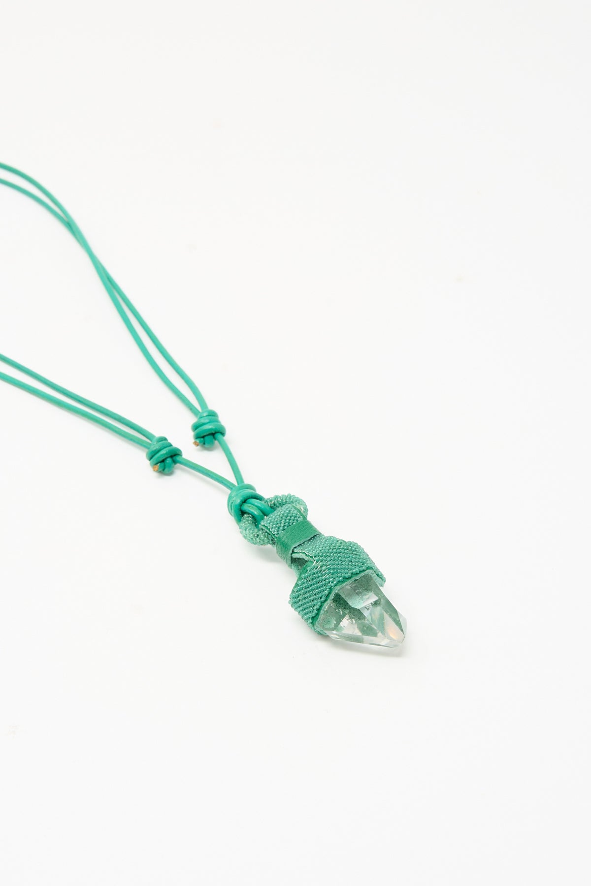 A Quartz Crystal Pendulum Necklace in Green featuring a clear crystal point pendant wrapped in teal cord on a matching cord.