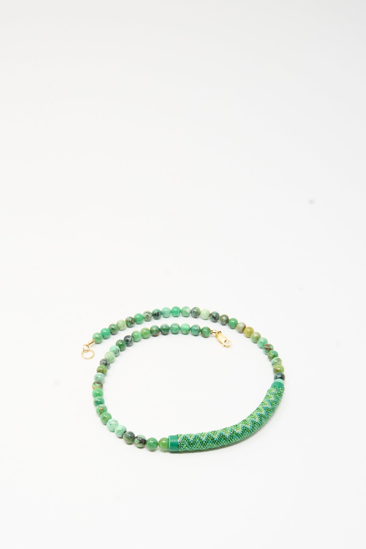 Handmade in New York, this Beaded Bar Necklace in Chrysoprase features green gemstone beads and a textured cylindrical bar with a geometric pattern.