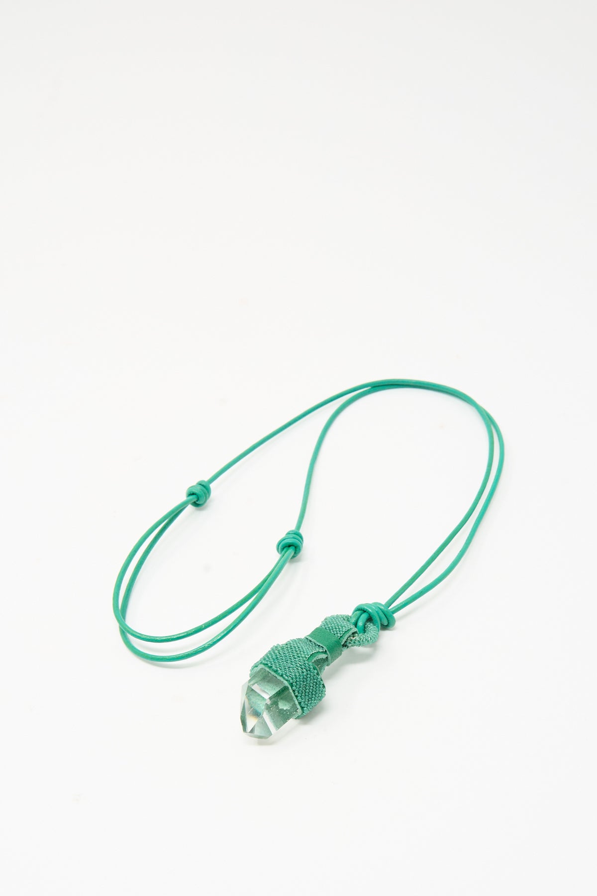 Robin Mollicone Quartz Crystal Pendulum Necklace in Green featuring a clear quartz crystal point hanging from a green woven cord.
