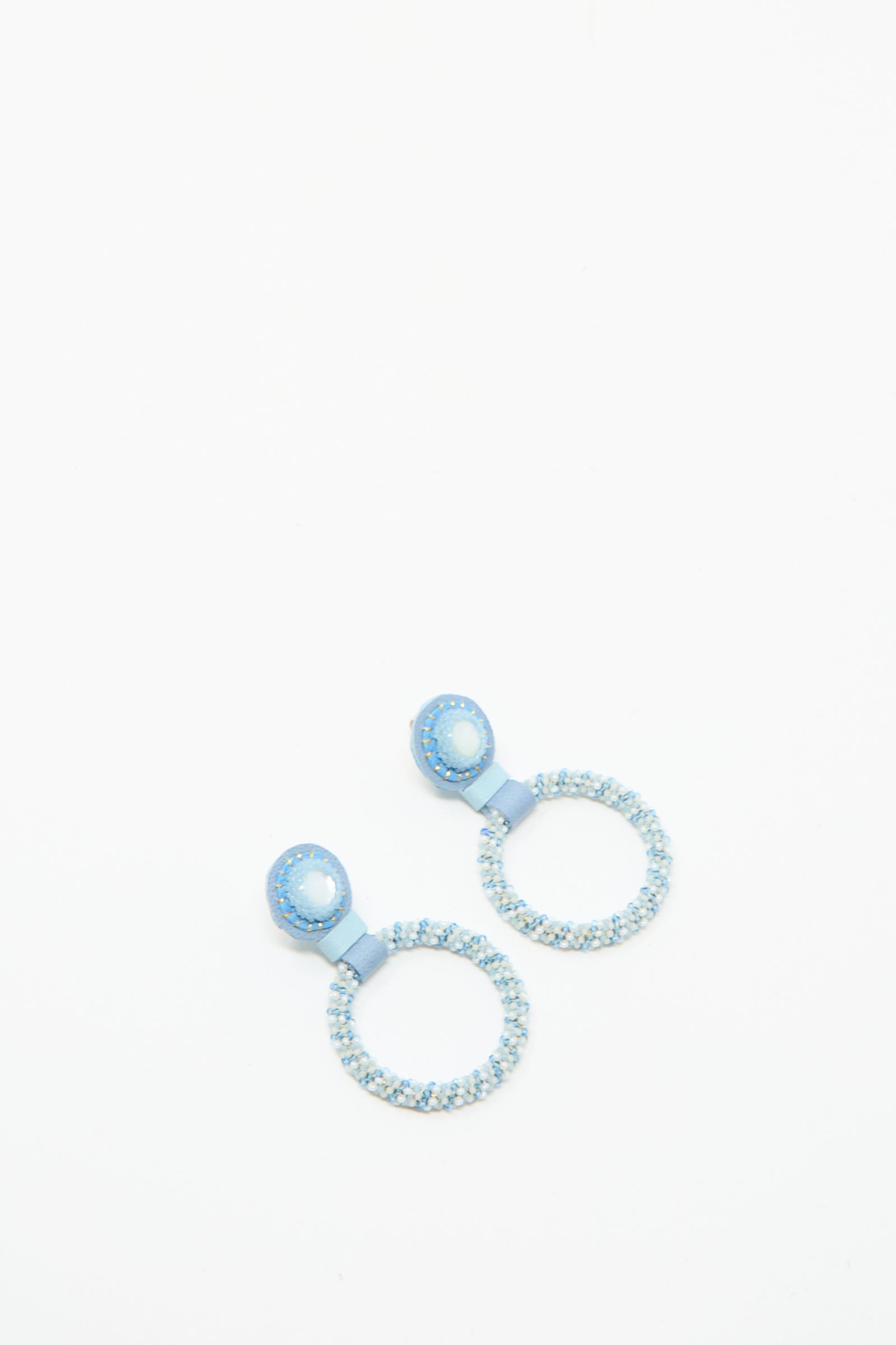 The Small Beaded Hoop Earrings in Mother of Pearl by Robin Mollicone are handmade in NYC, featuring light blue beaded hoops with solid blue circular studs, shown on a white background.