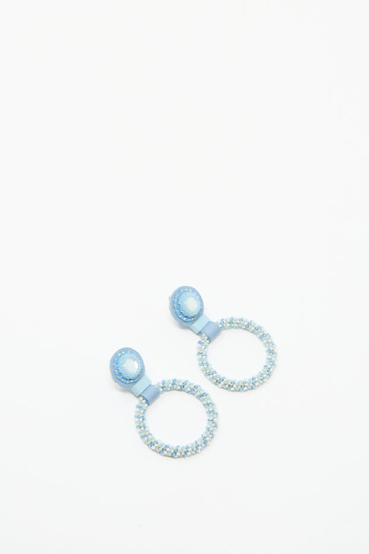 The Small Beaded Hoop Earrings in Mother of Pearl by Robin Mollicone are handmade in NYC, featuring light blue beaded hoops with solid blue circular studs, shown on a white background.