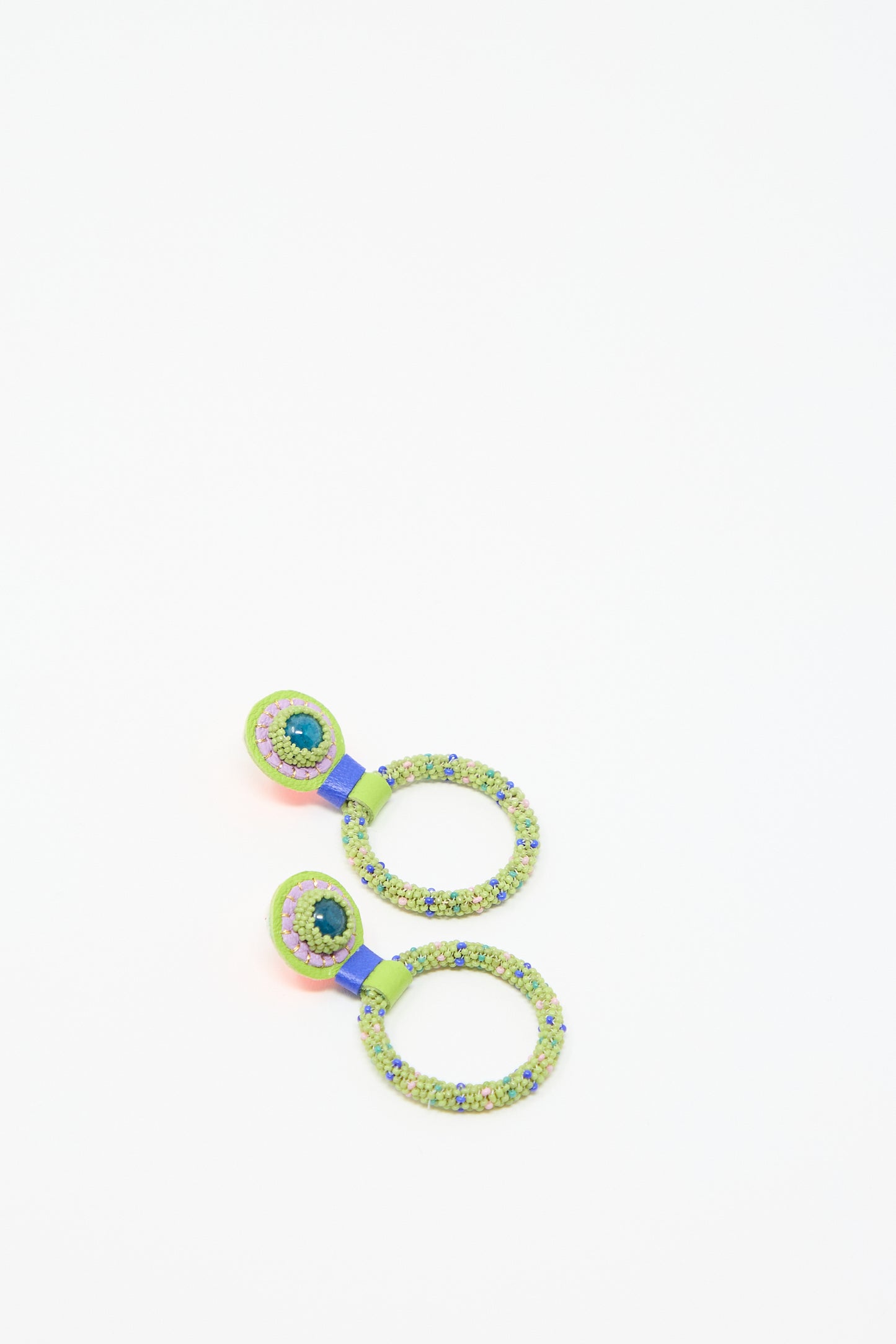 A pair of colorful, beaded earrings with small hoops and multi-colored beads, featuring a dominant green hue with accents of blue and pink, placed on a plain white background. The Small Beaded Hoop Earrings in Olive Dots with Apatite Stone Tops by Robin Mollicone are adorned with apatite stones and finished with sterling silver posts for an elegant touch.