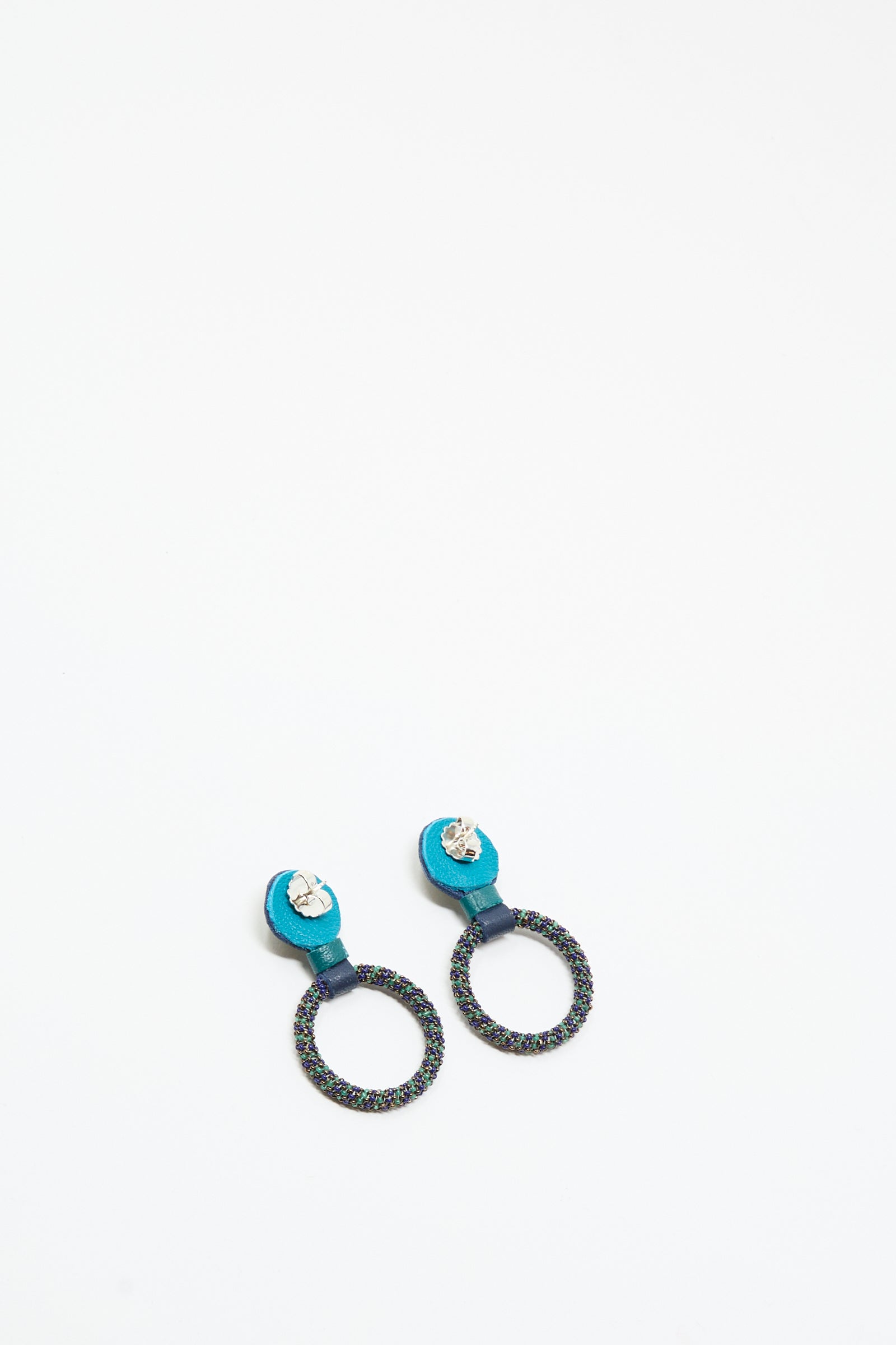 The Small Beaded Hoops in Blue with Lapis by Robin Mollicone are handmade in NYC, featuring textured blue and black hoops with small clear studs, shown on a plain white background.