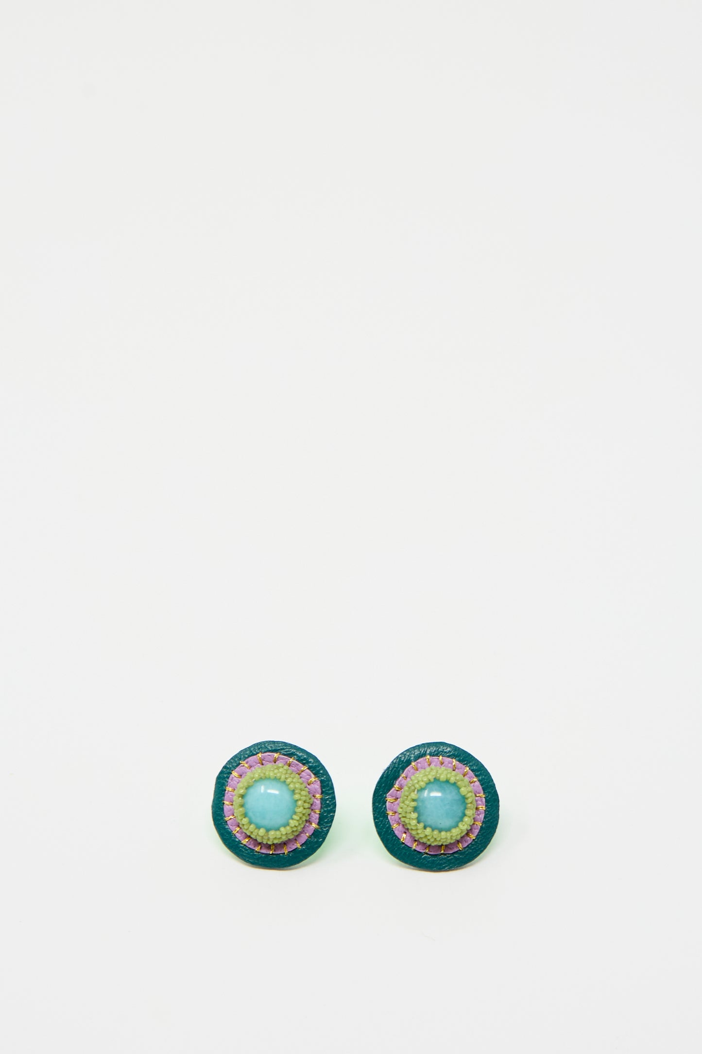 Introducing the Robin Mollicone Stud Earrings in Amazonite: a pair of round, handmade earrings featuring a central amazonite blue bead, an outer border of green beads, and multiple colorful rings in between, all set against a plain white background.