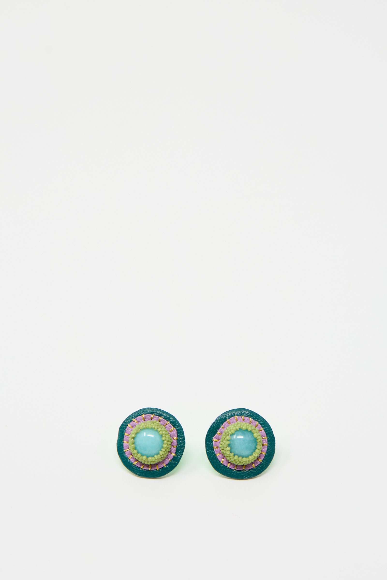 Introducing the Robin Mollicone Stud Earrings in Amazonite: a pair of round, handmade earrings featuring a central amazonite blue bead, an outer border of green beads, and multiple colorful rings in between, all set against a plain white background.